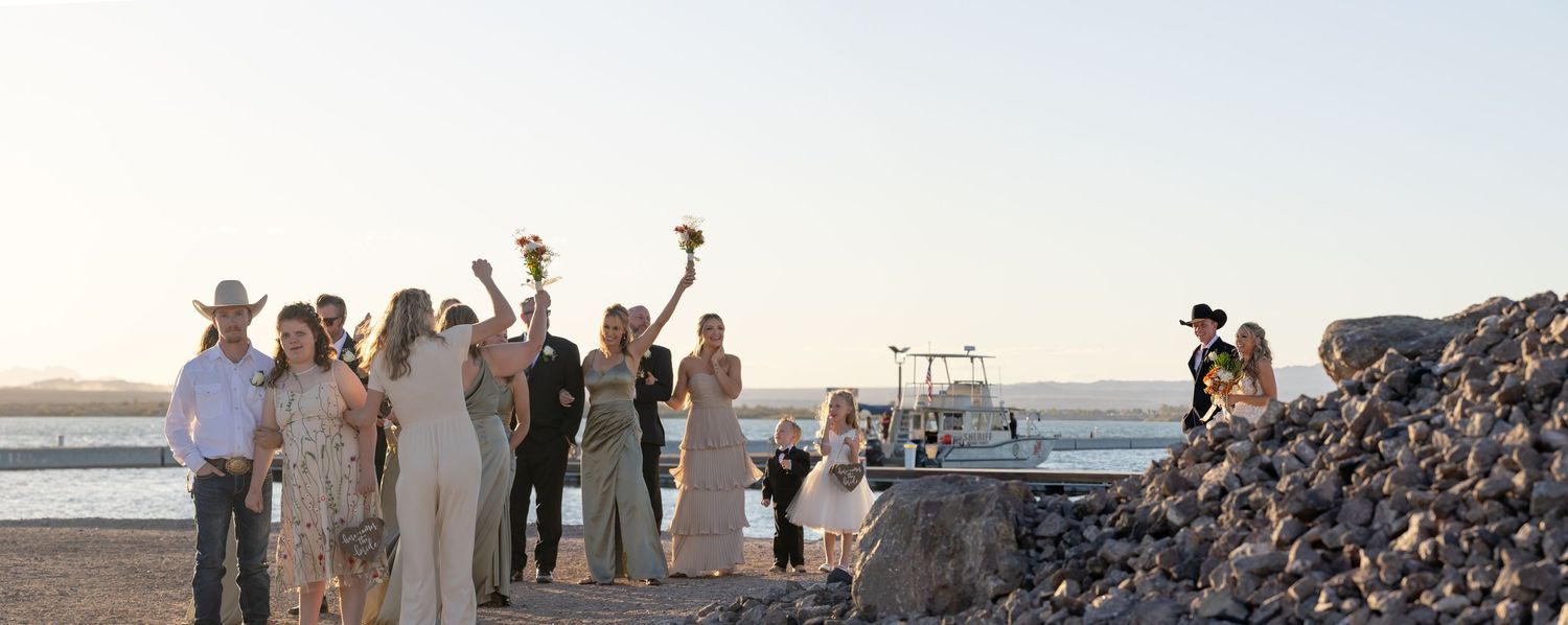 A wedding party gathers at the Riviera Marina at sunset near the water to celebrate and take photos in Lake Havasu City Arizona