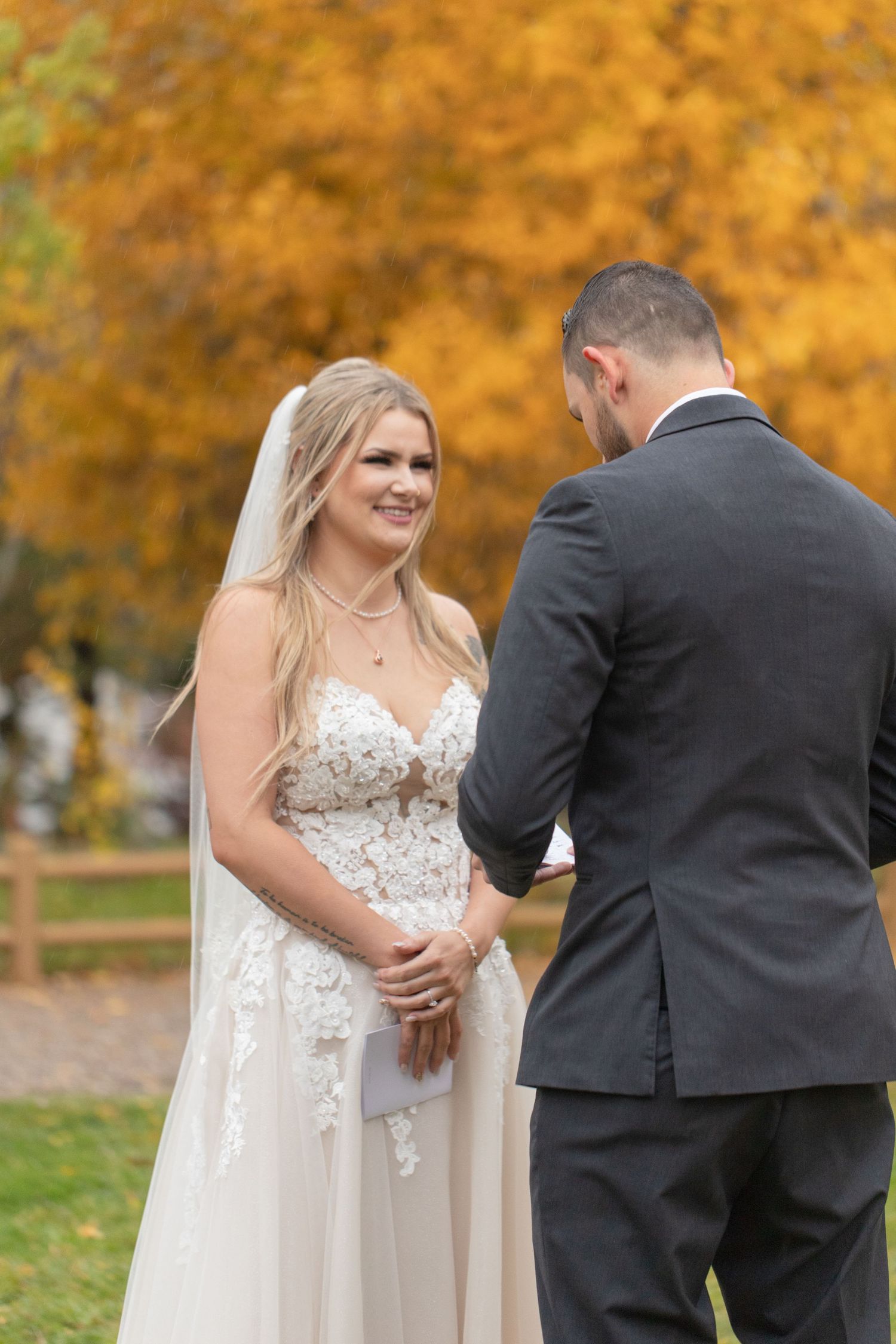 Autumn wedding scene with couple sharing intimate moment against backdrop of golden leaves.