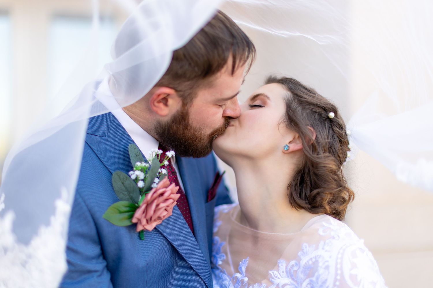Romantic wedding moment captured as couple shares kiss under flowing veil. shot by lake havasu photographer arianna hosea