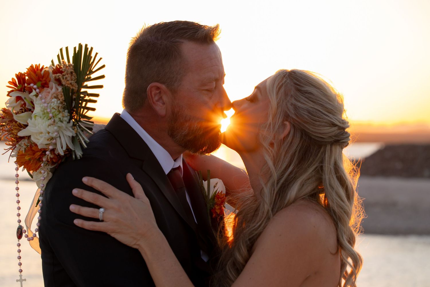 Romantic sunset embrace of couple with bridal bouquet at The Riviera Marina, Lake Havasu wedding.