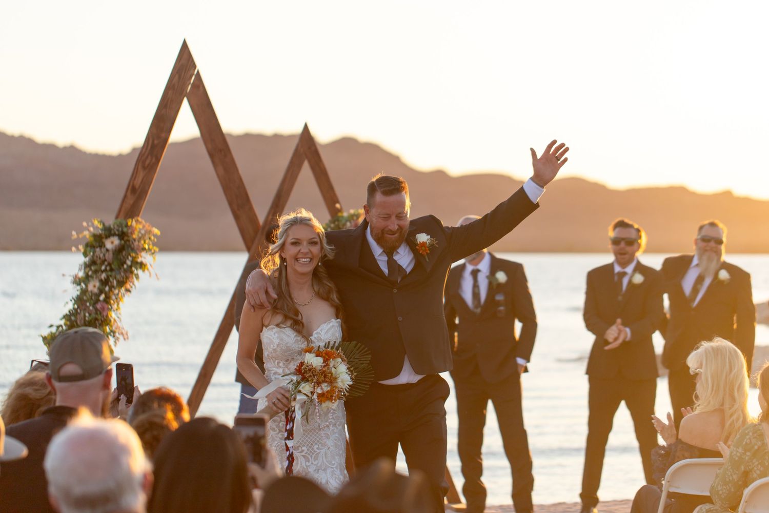 Wedding ceremony celebration in Lake Havasu City Arizona at the Riviera under wooden triangular arches against a sunset waterfront backdrop.