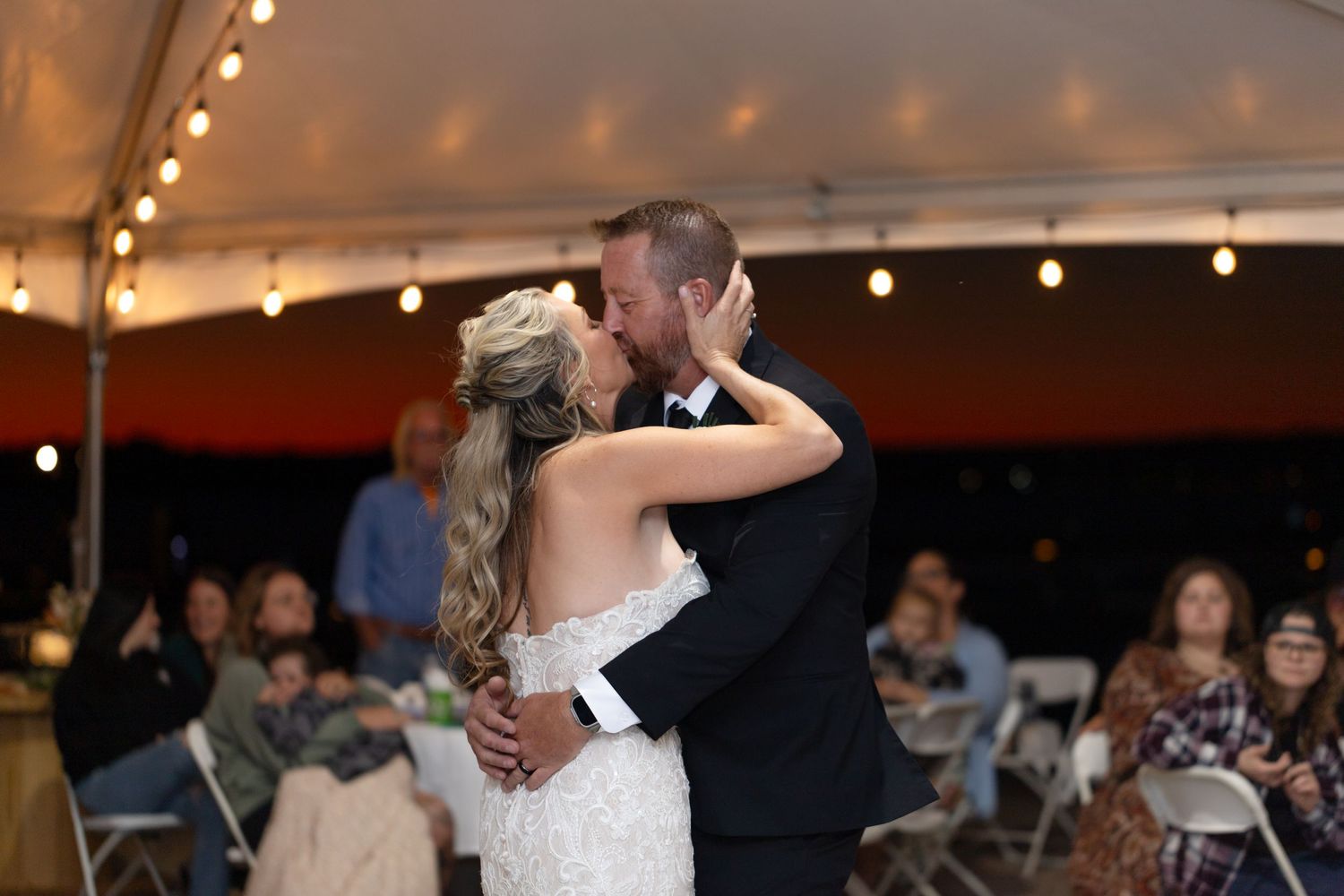 Romantic first dance under tent with string lights at evening wedding reception, The Riviera Marina.