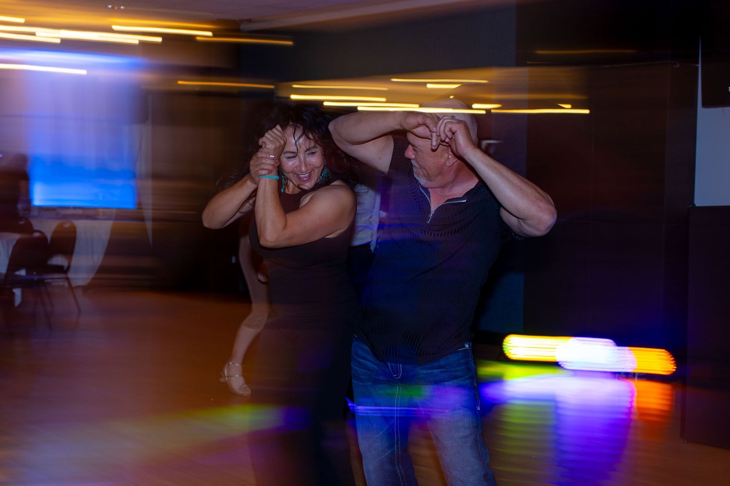 Couple dancing energetically on a colorful dance floor with motion blur and vibrant neon lights at Shugrues in Lake Havasu