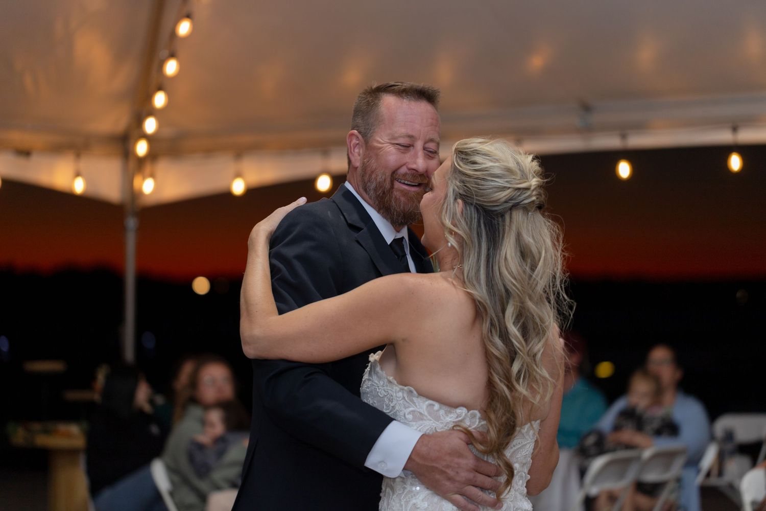 Sweet dance moment between couple under string lights in indoor venue, Lake Havasu wedding.