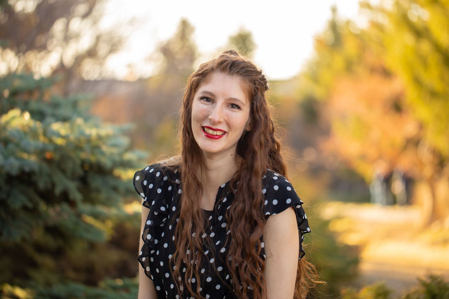 Portrait series of woman in polka dot dress smiling outdoors during autumn.