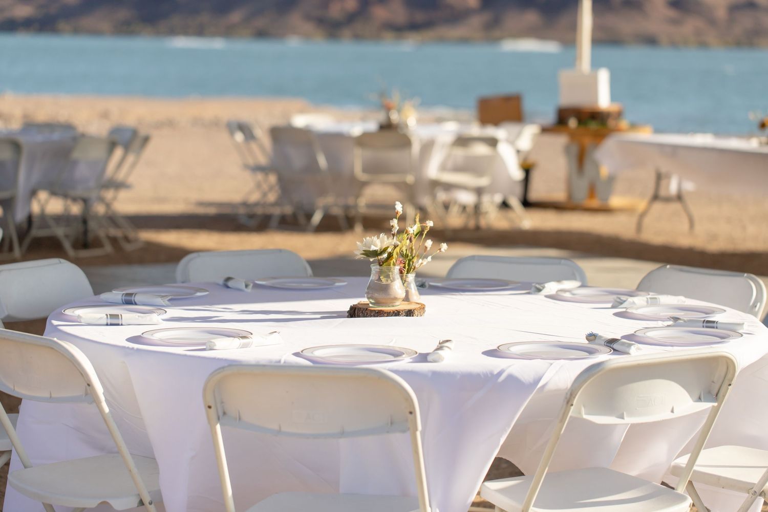 White round tables with chairs set up for an outdoor waterfront event with decorative centerpieces in Lake Havasu City Arizona