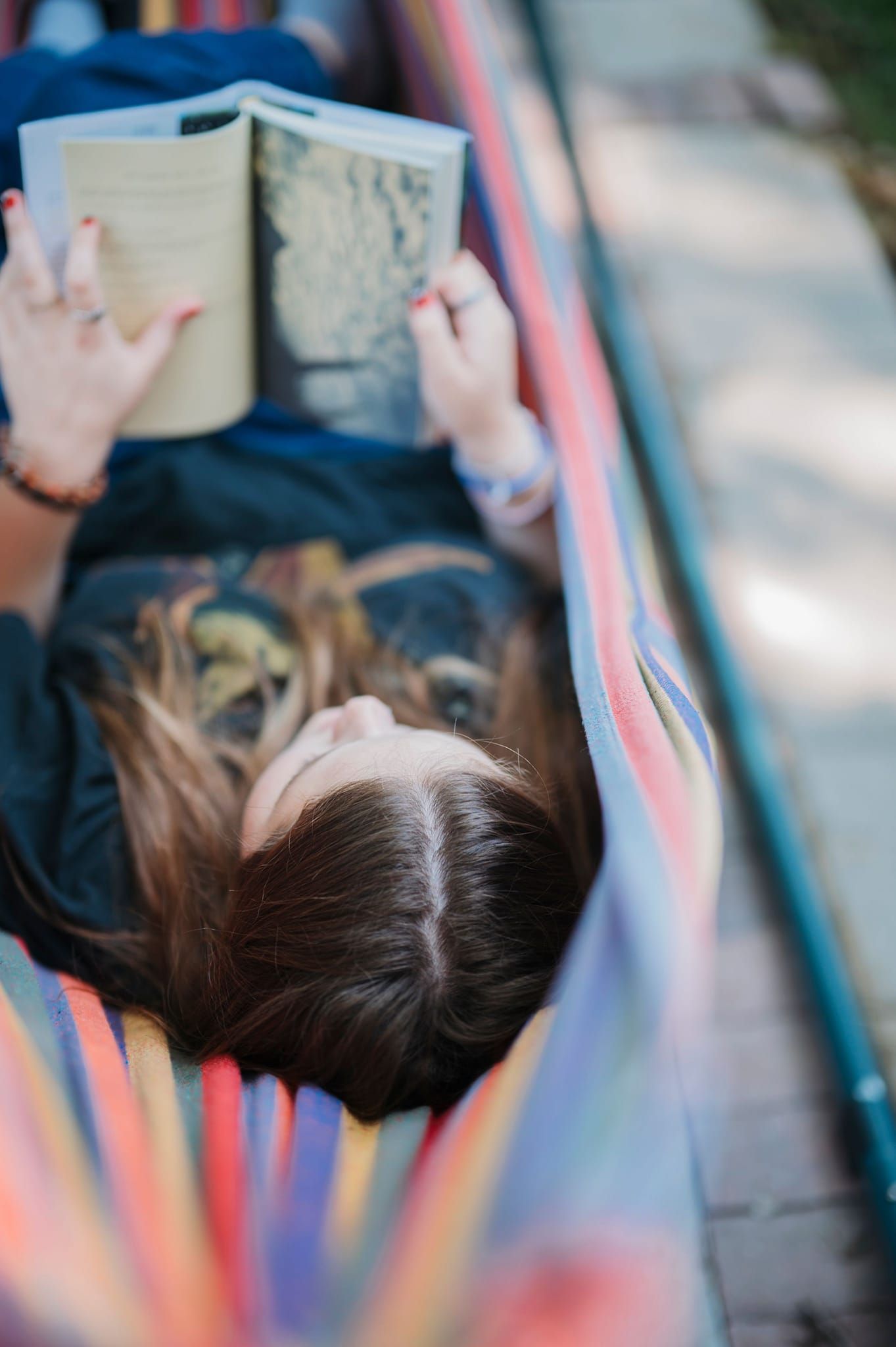 senior reading and laying in a hammock during their senior photoshoot with ninefifteenphoto