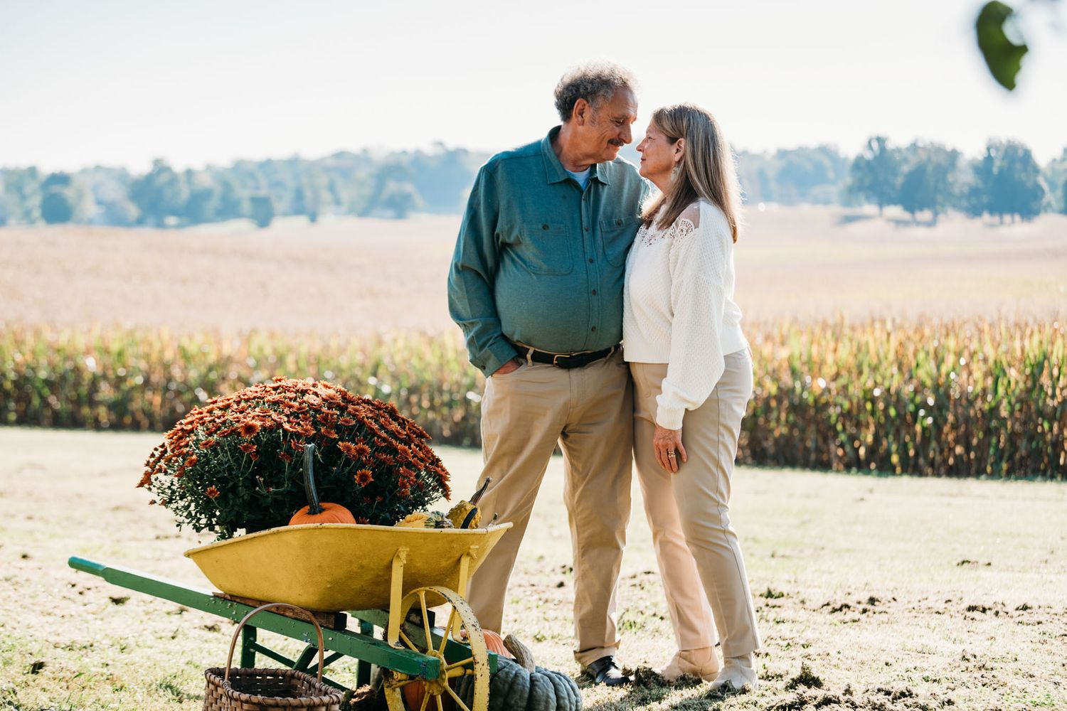 Couple smiling beside pumpkins and fields during cozy fall family photo session in Meade County KY.