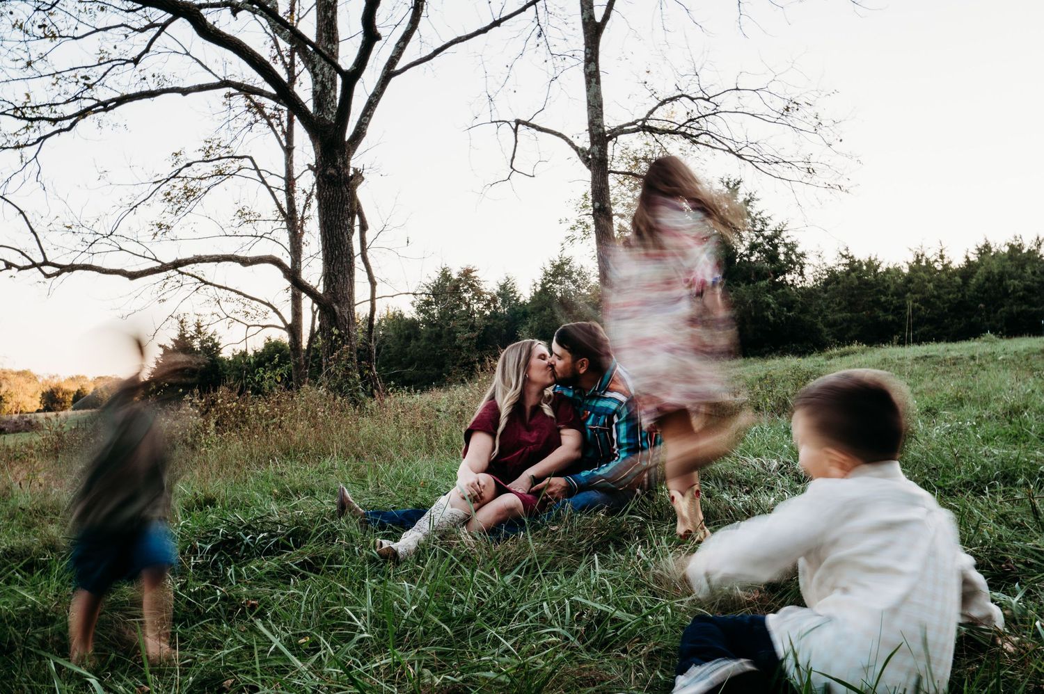 Family laughing and playing together in grassy field at sunset in Guston Kentucky