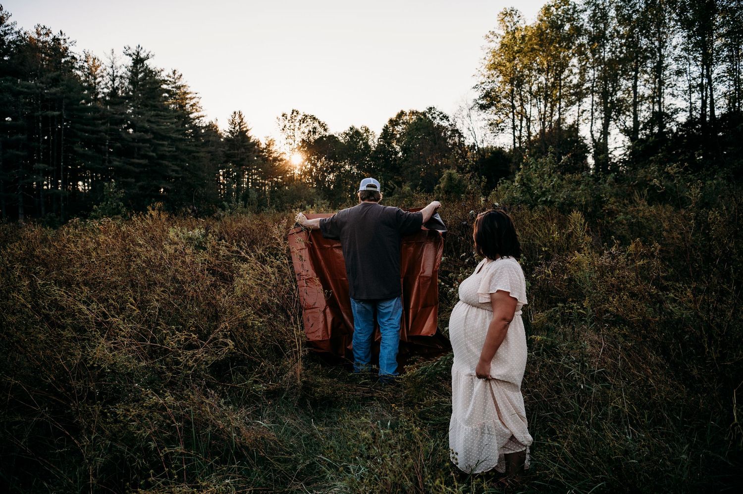 Family standing together in tall grass during outdoor maternity session Otter Creek