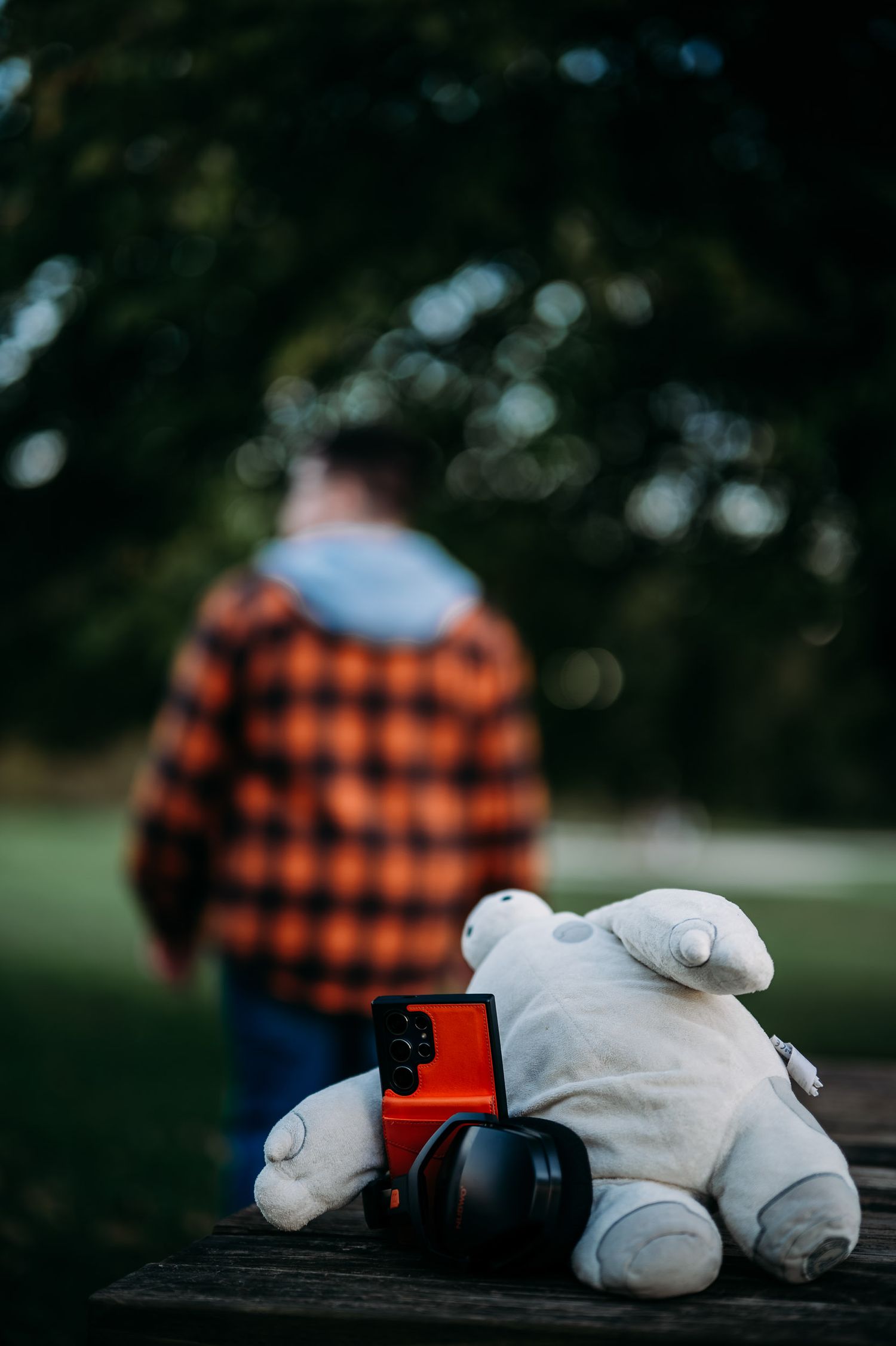 Luca walking in an orange flannel beside his Baymax plush toy during his Brandenburg KY senior photo session.