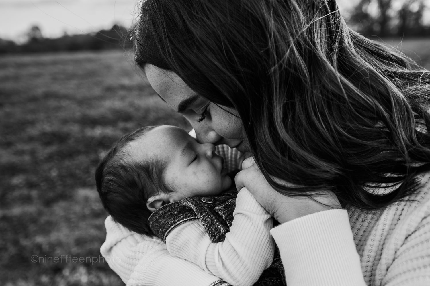 Black and white mother kissing newborn baby outdoors, Kentucky lifestyle newborn photographer in Meade County.