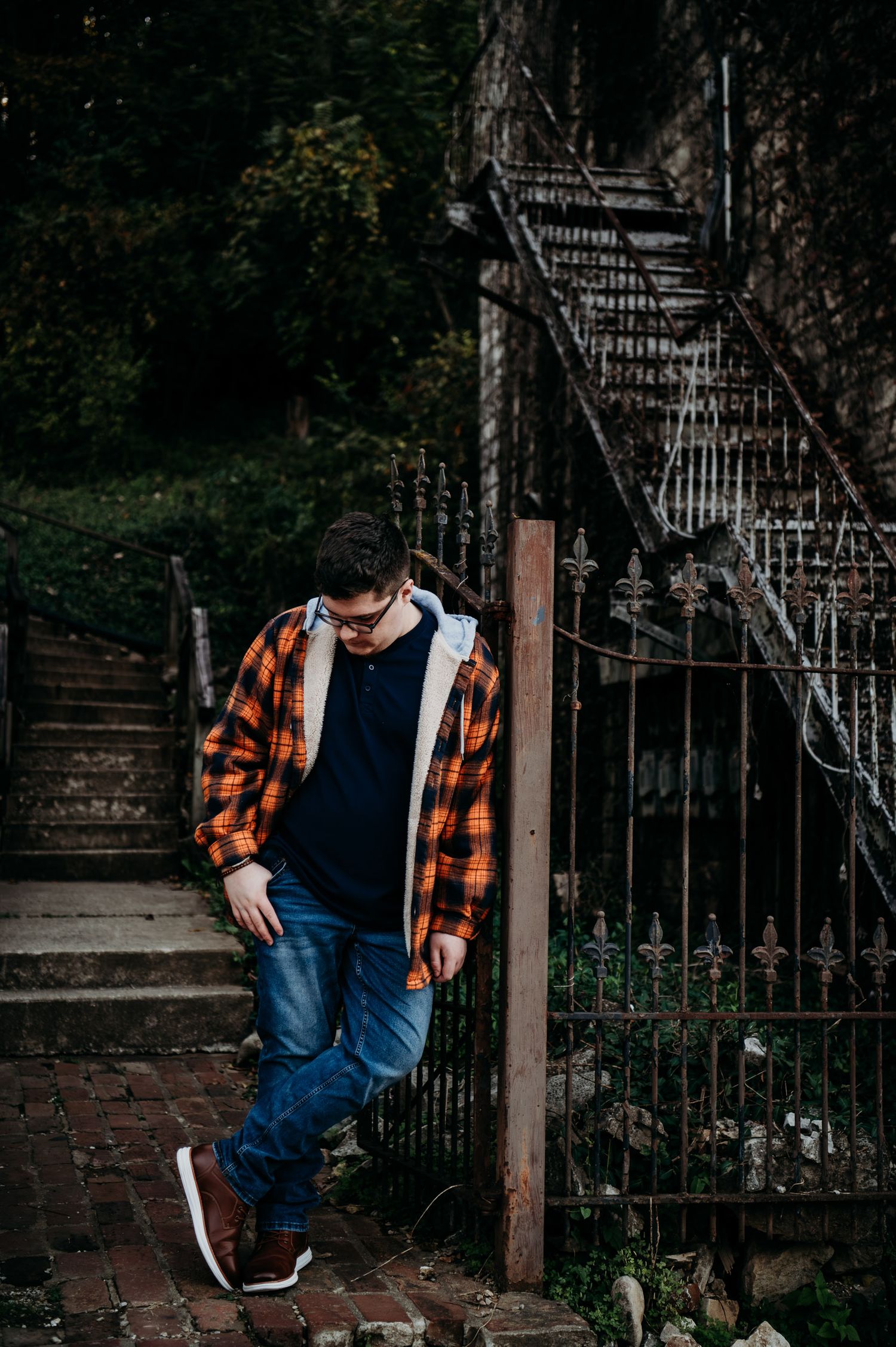 Luca leaning against a brick and iron gate in downtown Brandenburg KY during his fall senior session.