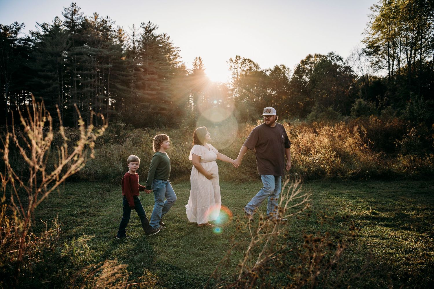 Family walking through golden light during fall maternity session in Brandenburg KY