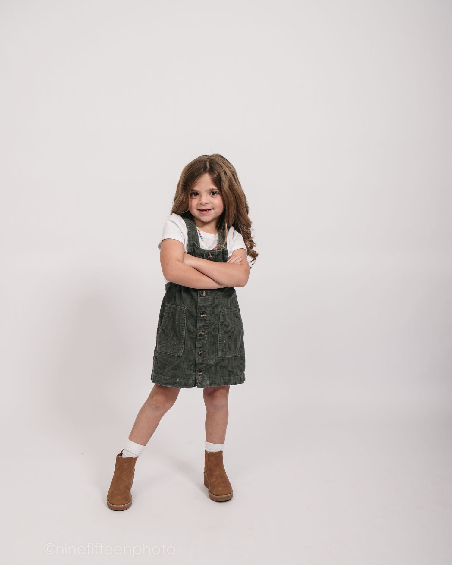 Studio personality portrait of a young girl smiling confidently in a textured vest against a neutral studio backdrop in Meade County KY