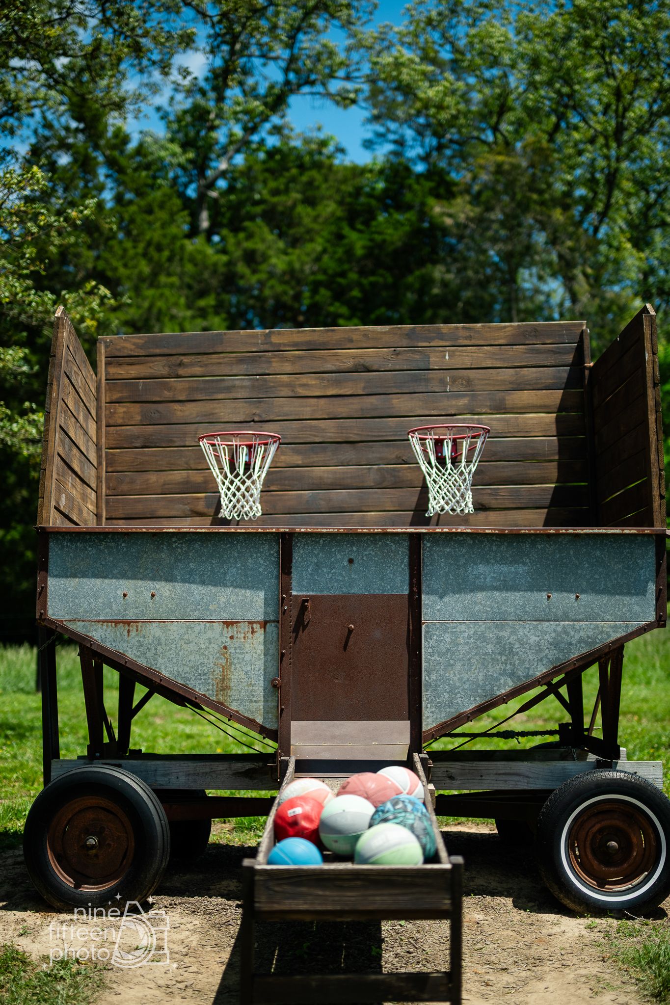 Rustic wooden basketball carnival game with colorful balls outside at Hardesty Farms & Greenhouses.