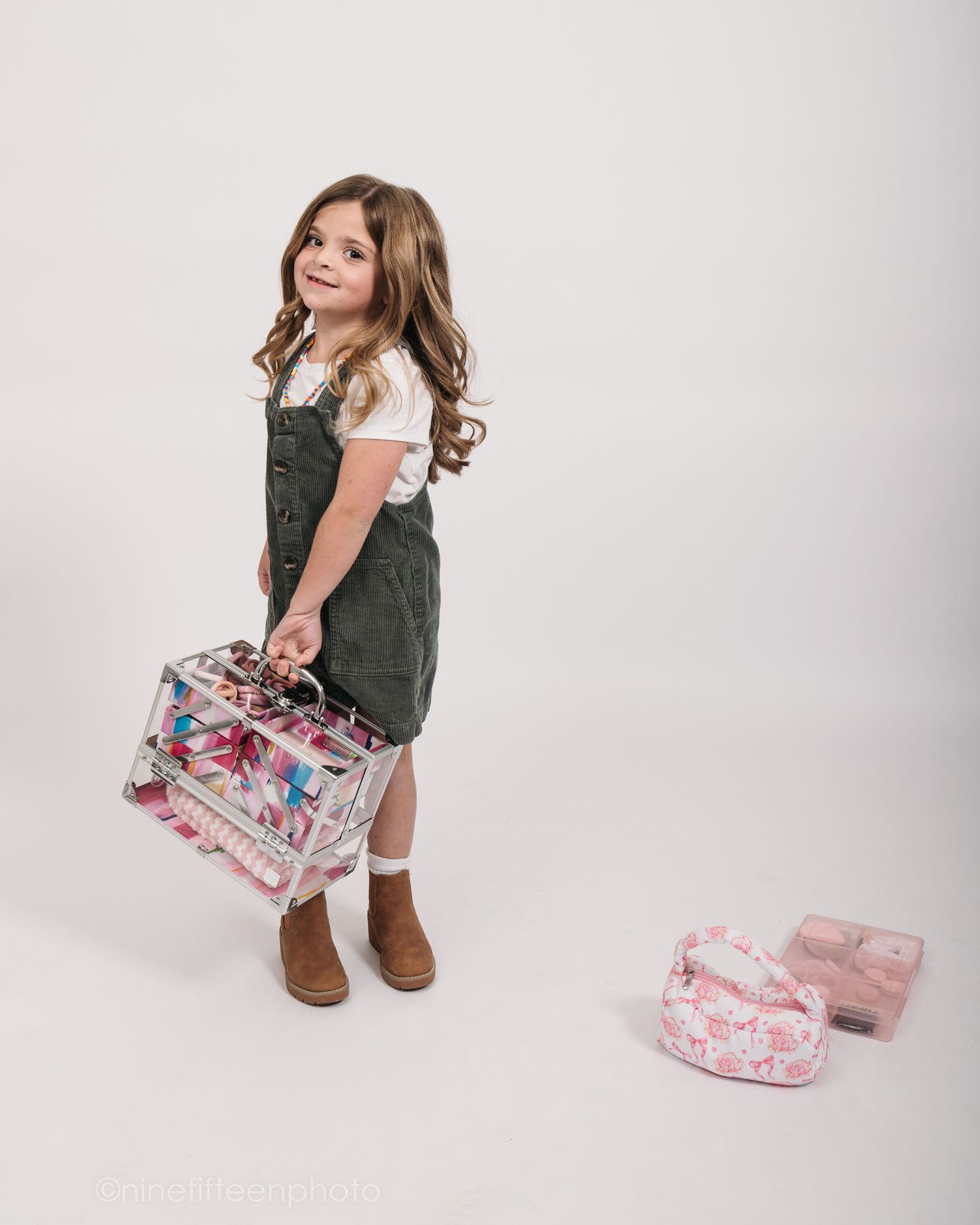 Studio personality portrait of a young girl smiling confidently in a textured vest against a neutral studio backdrop in Meade County KY