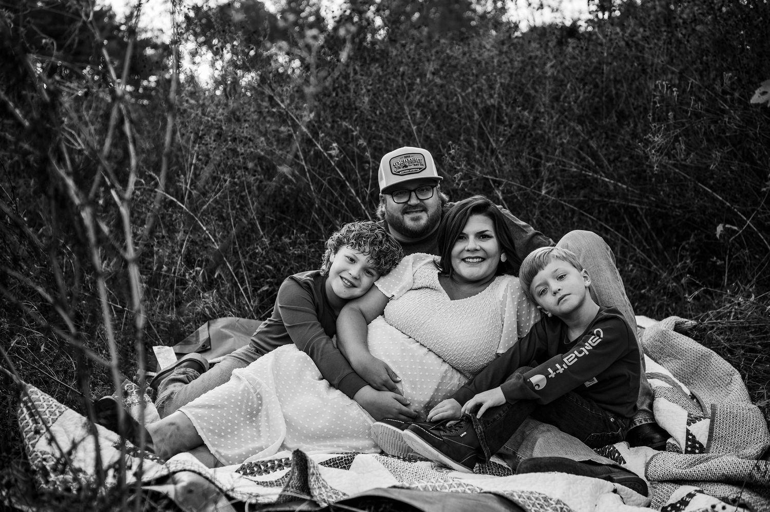 Cozy family moment on a blanket during outdoor maternity session at Otter Creek