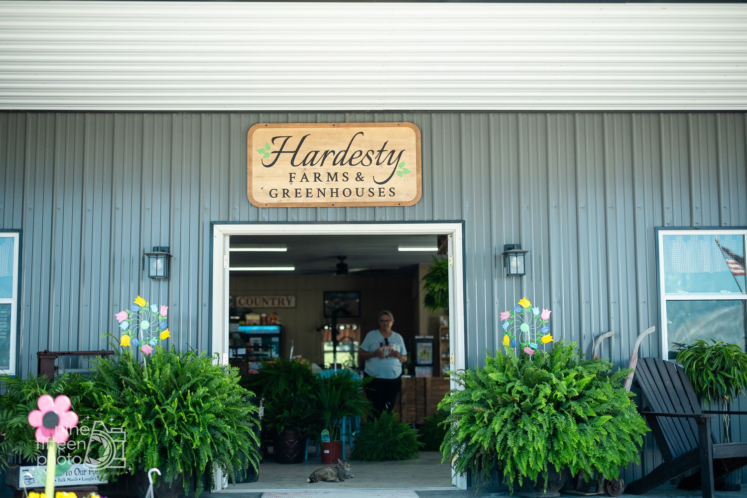 Entrance to Hardesty Farms & Greenhouses with lush greenery and colorful flowers in Brandenburg, KY.