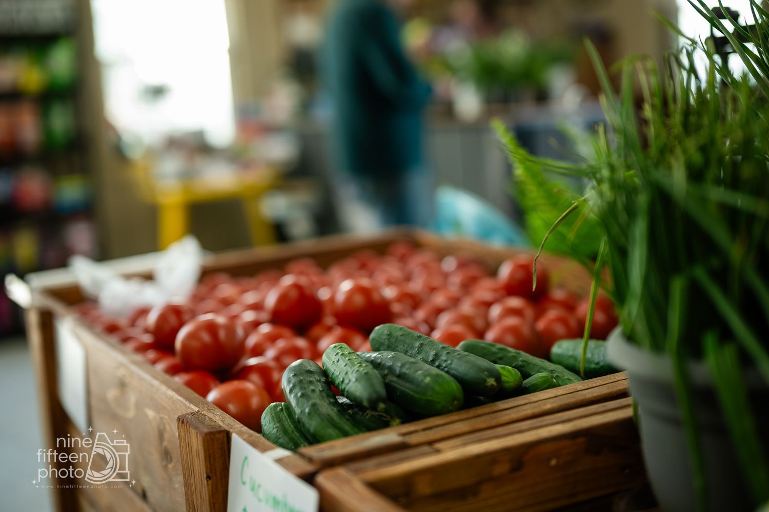 Fresh red tomatoes and cucumbers displayed in rustic wooden crates at Hardesty Farms farmers market.