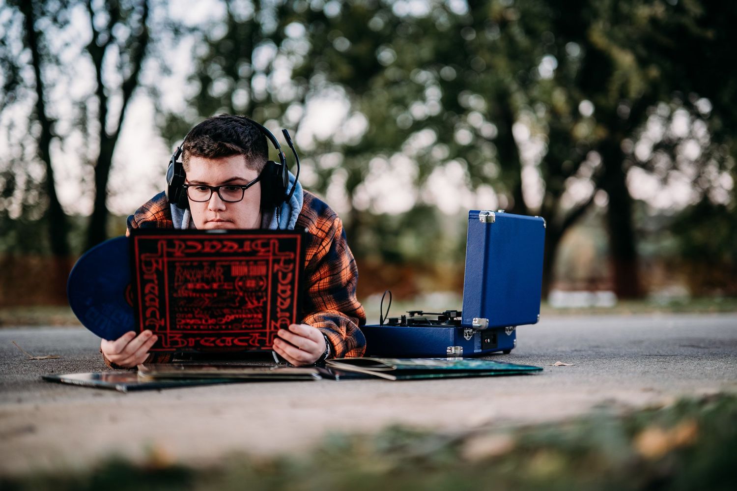 Senior photo of Luca with his record player and vinyls laid out on the ground in Brandenburg KY.