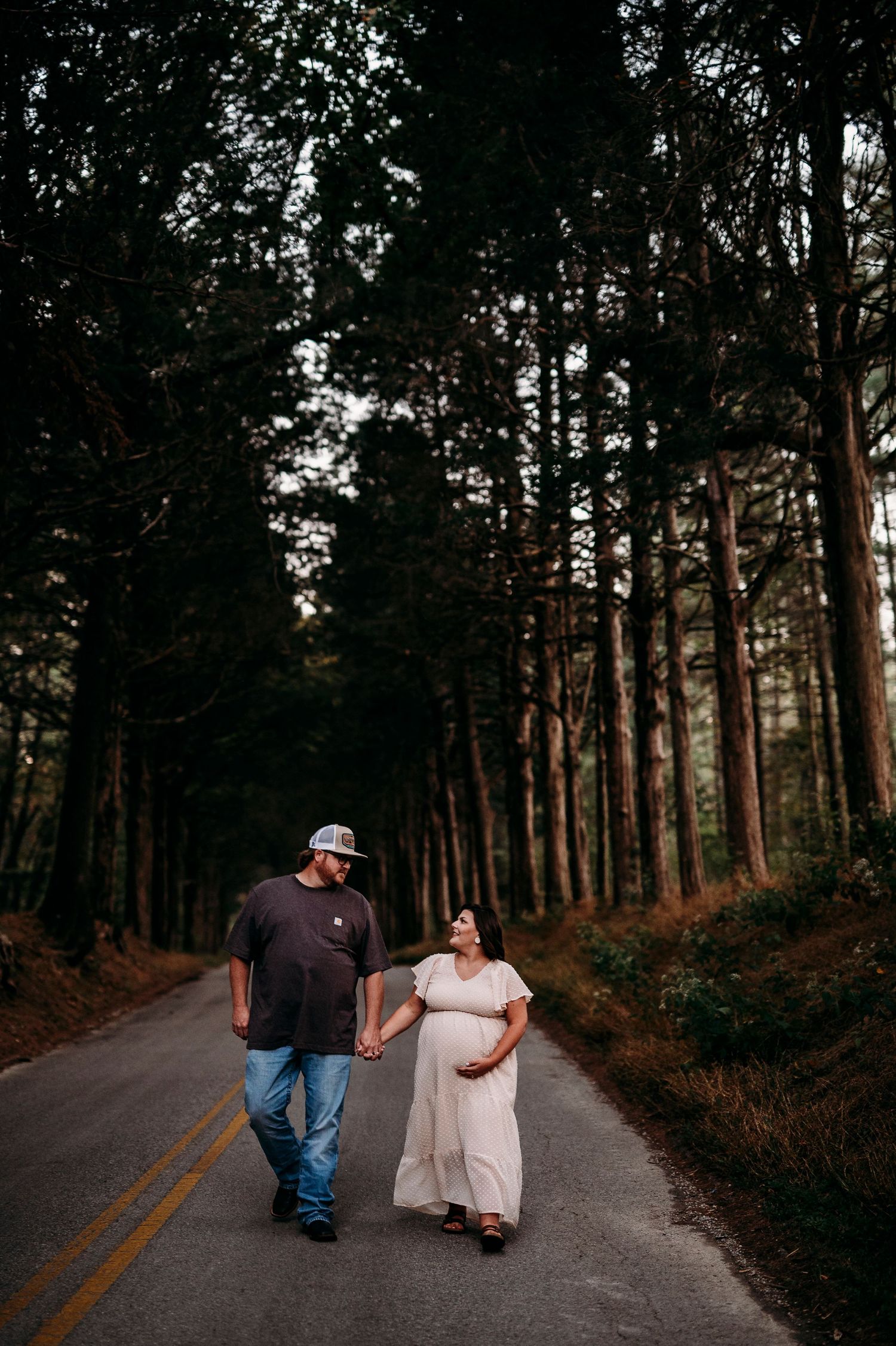 Couple walking through wooded path during golden hour maternity photos Otter Creek