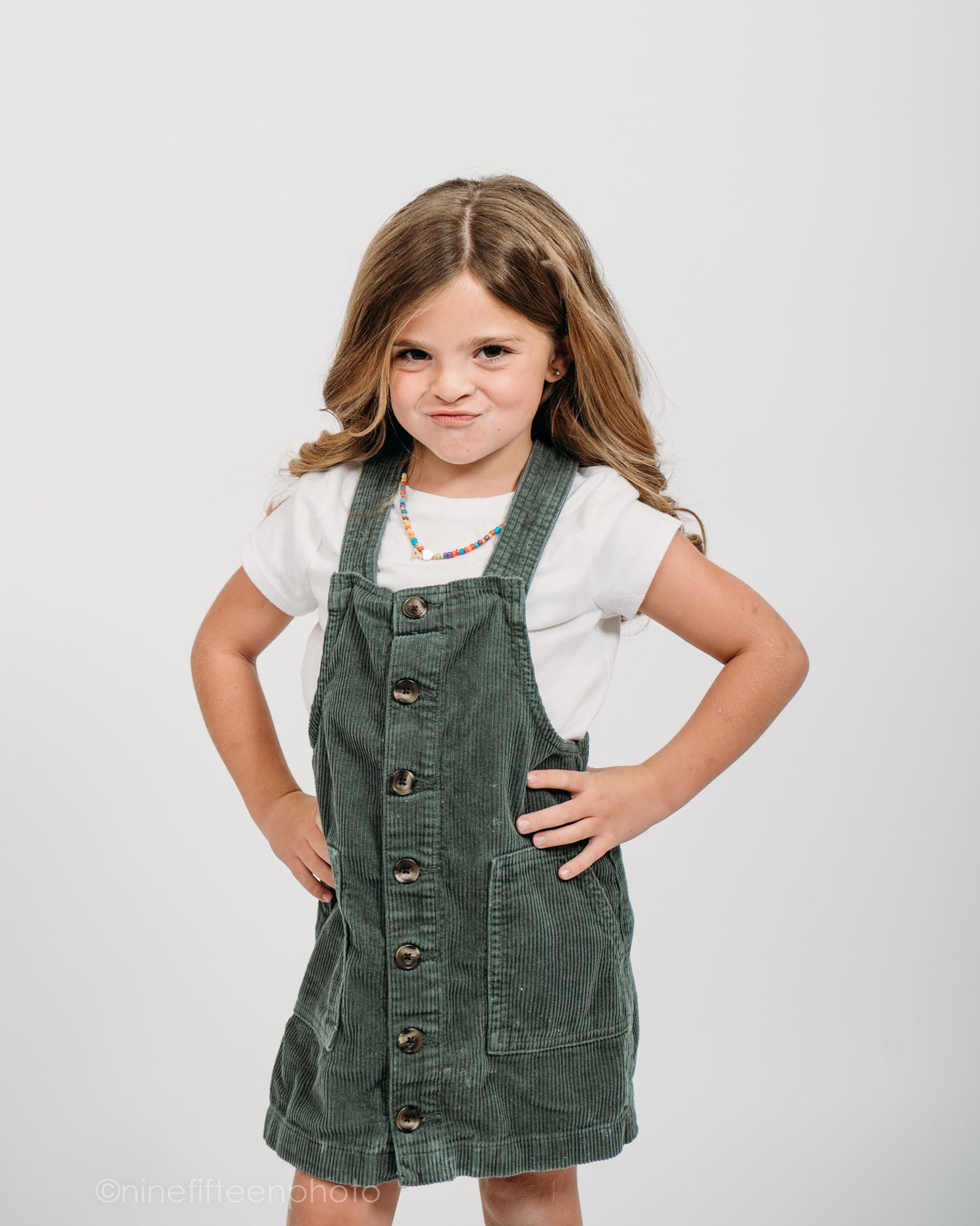 Studio personality portrait of a young girl smiling confidently in a textured vest against a neutral studio backdrop in Meade County KY