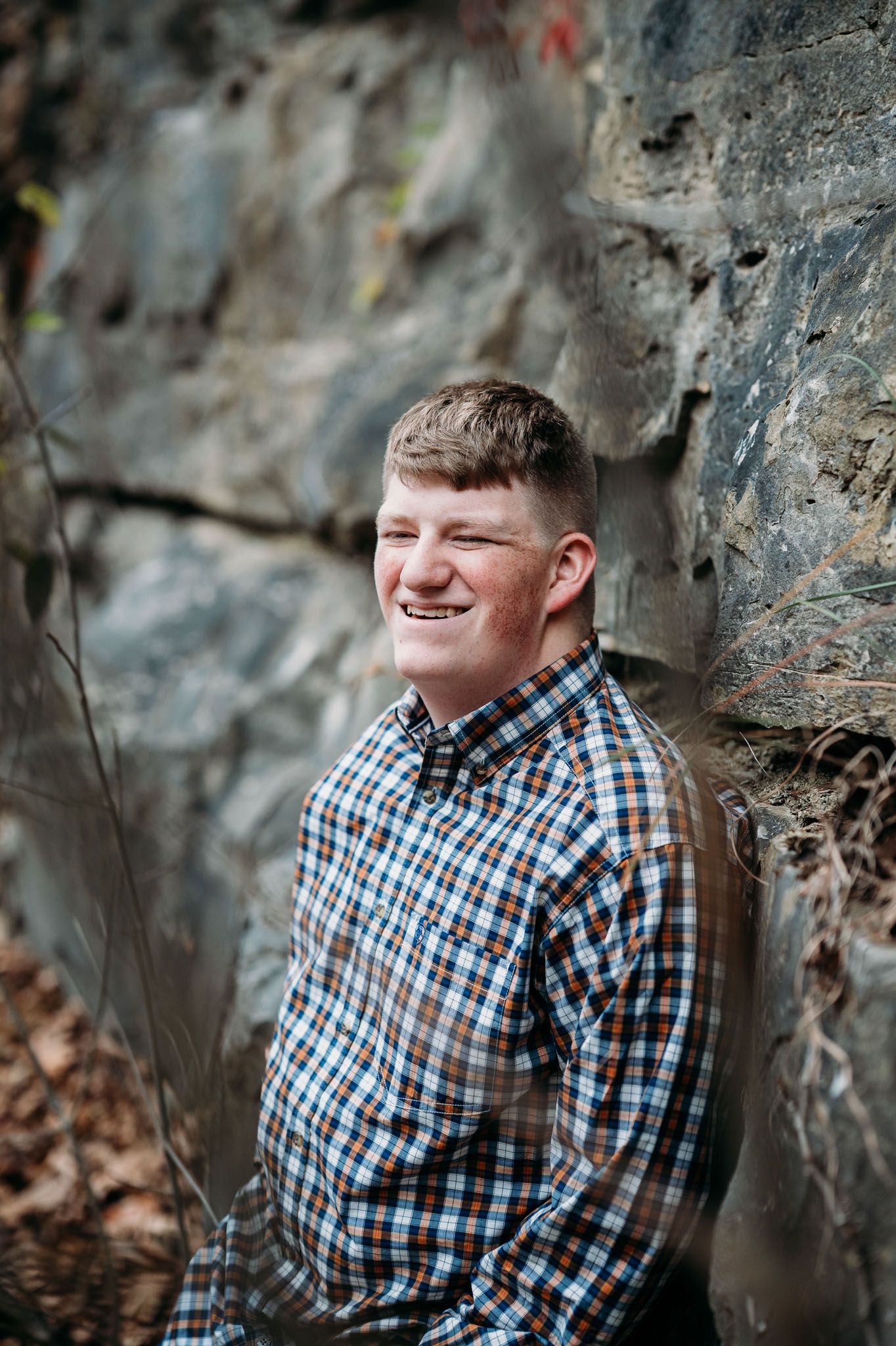 Mayson smiles beside a rock wall during his Meade County senior portraits