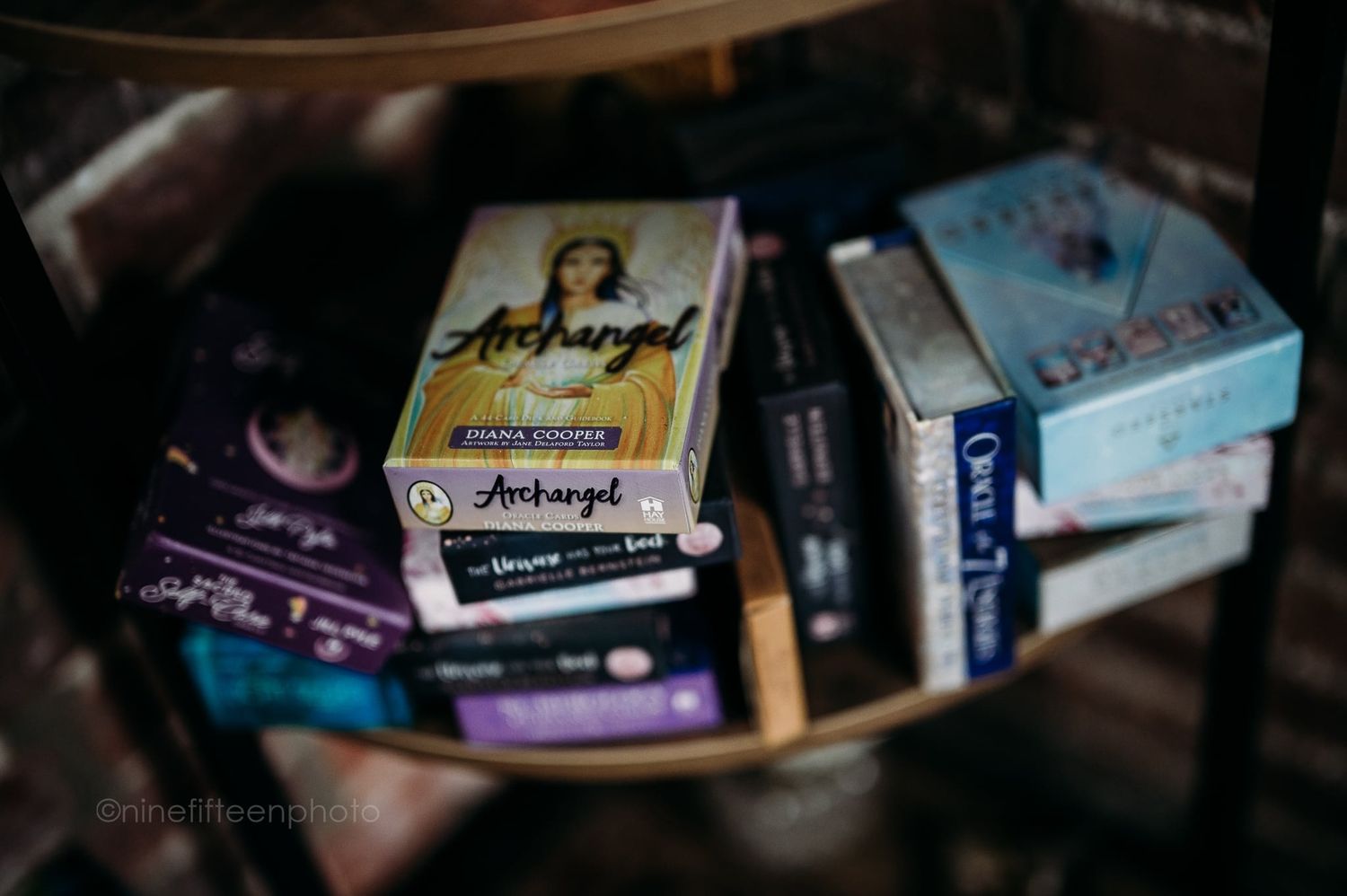 Close-up of Archangel oracle cards and spiritual books arranged on a glass table.