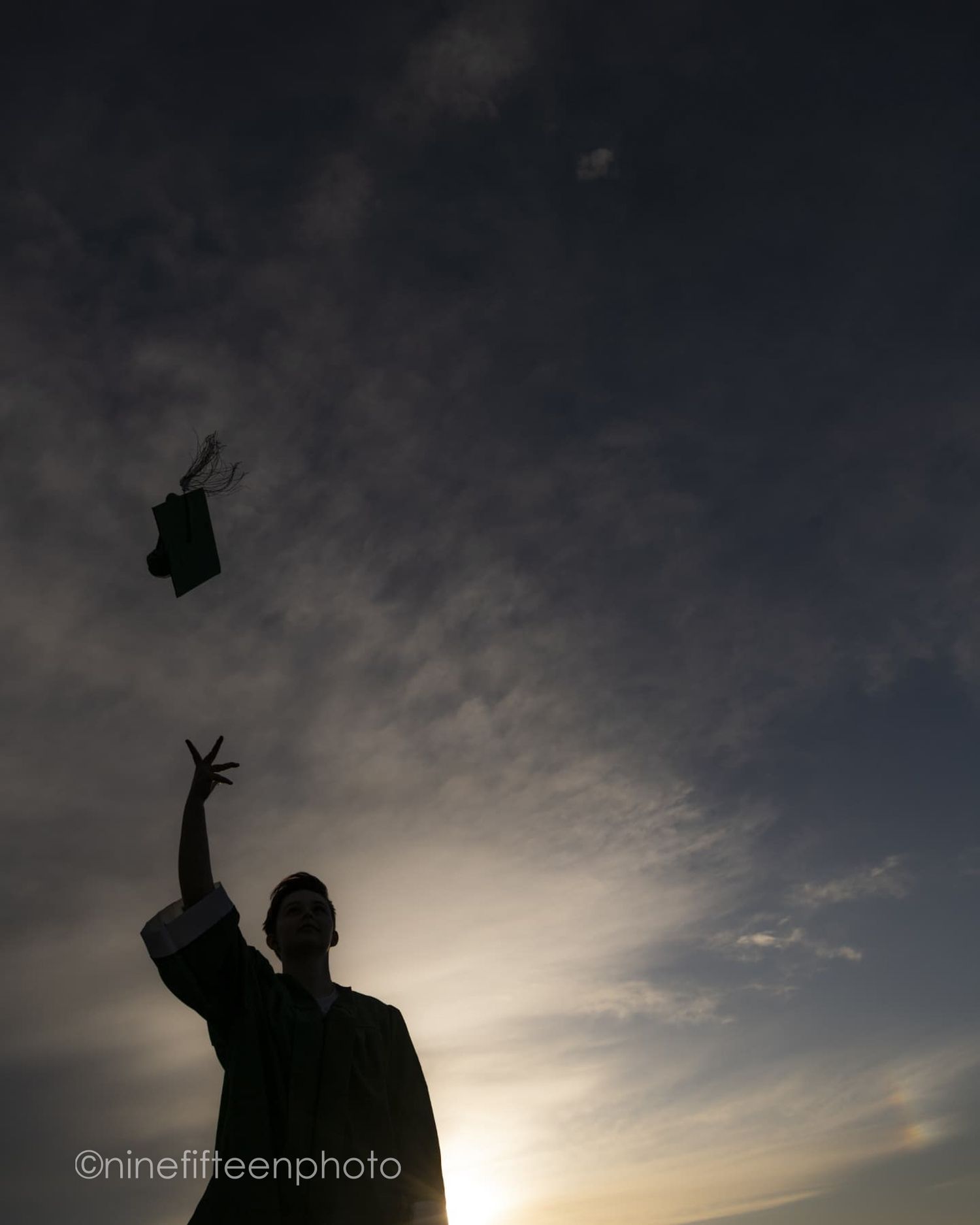 Silhouette of a graduate tossing their cap into a dramatic sunset sky.
