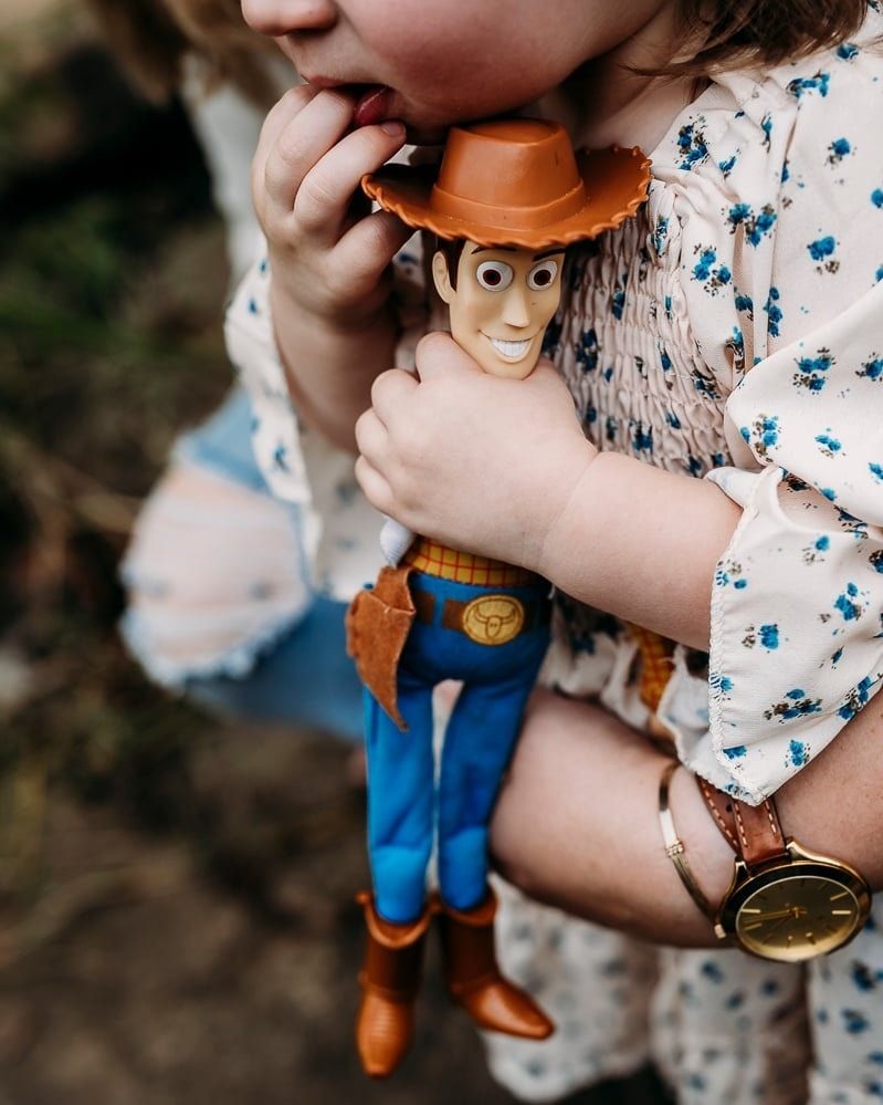 Child holding Woody toy close during relaxed family photo session in Brandenburg KY.