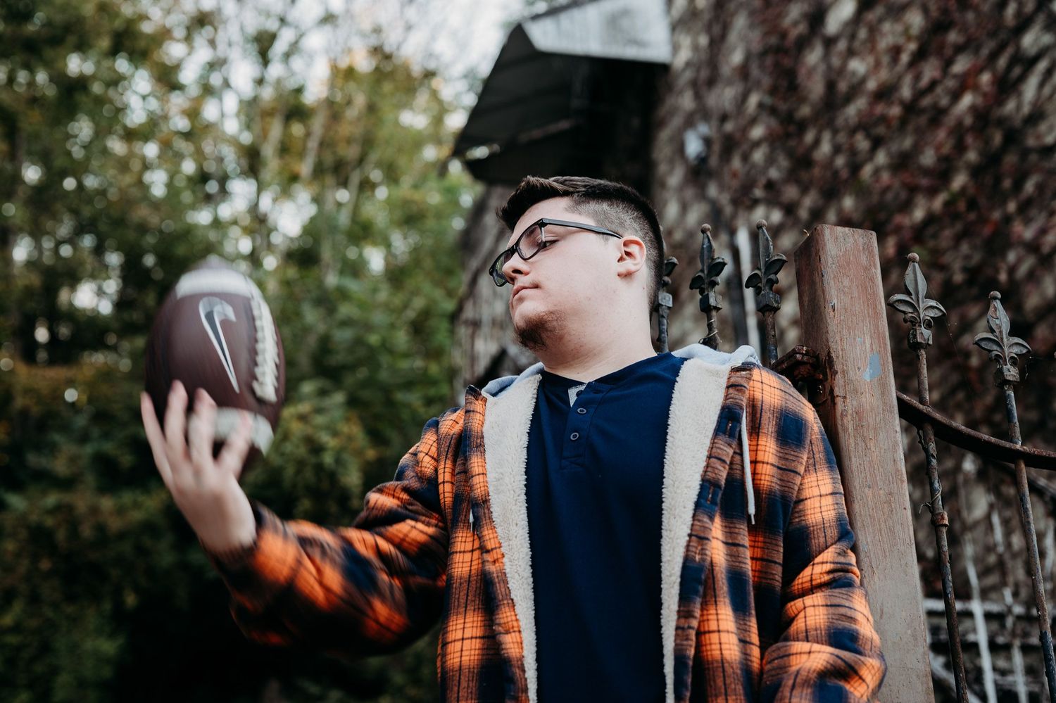 Luca throwing a football in his orange flannel during his downtown Brandenburg KY senior session.