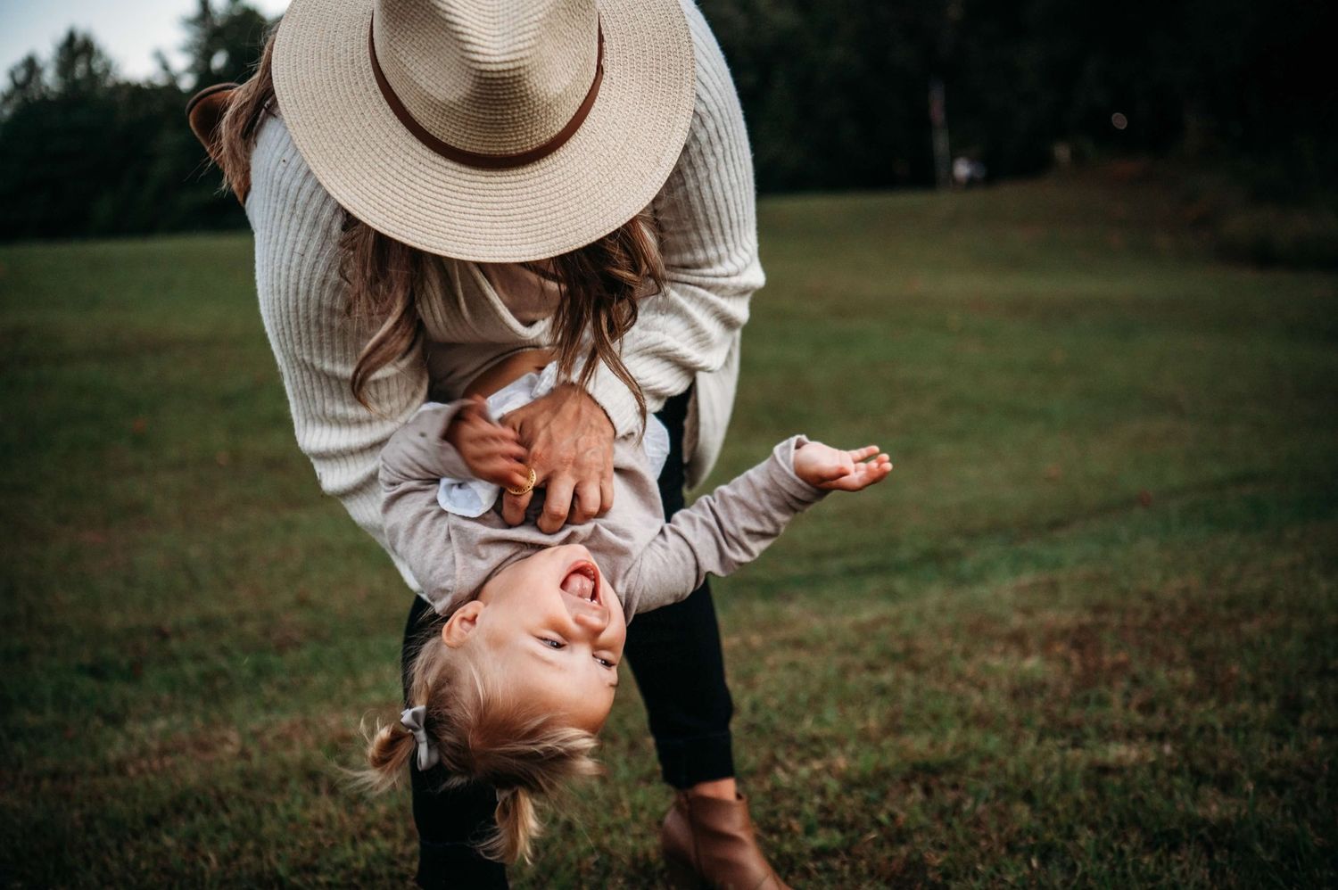 Parent laughing while playfully flipping child upside down during outdoor family photo session in Brandenburg KY.