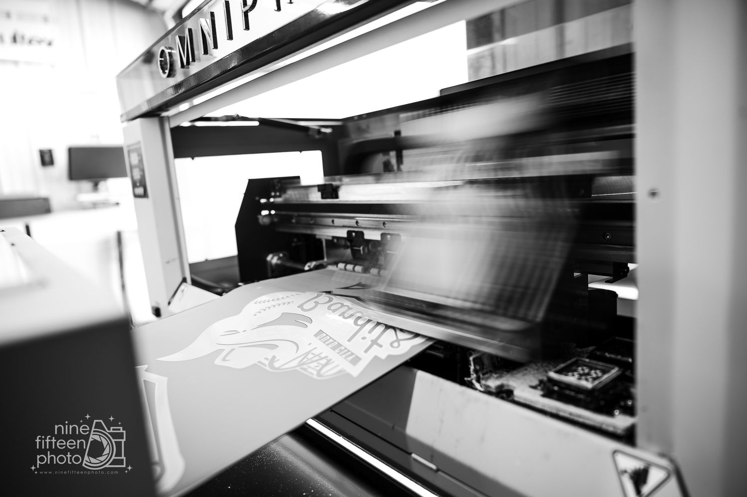 Black and white photo of commercial printing press running inside MC Screen Printing in Brandenburg Kentucky.