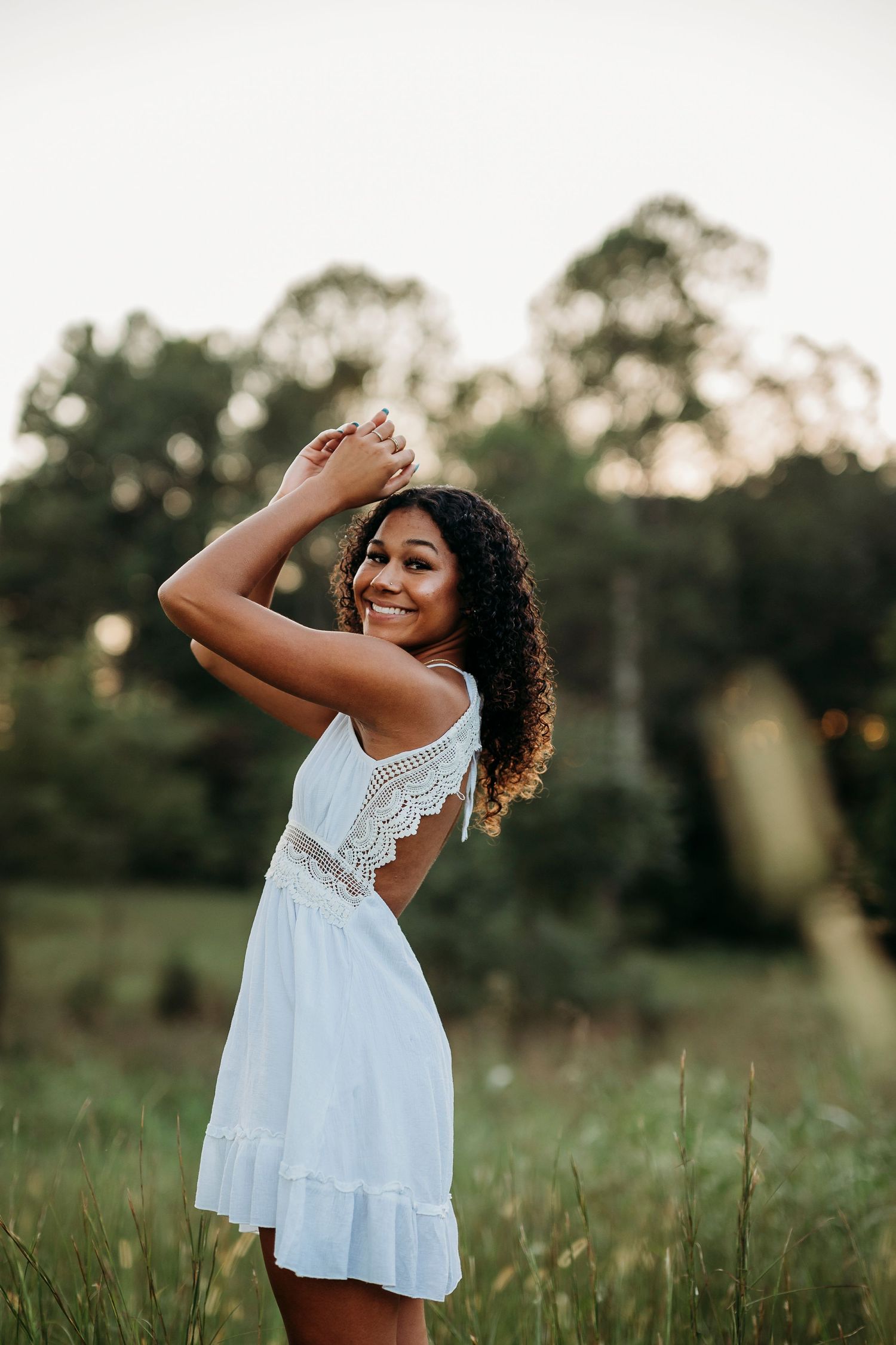 Bella in white dress posing in open field during Brandenburg KY senior photo session by ninefifteenphoto