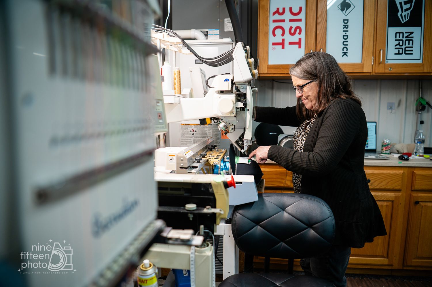Woman operating embroidery machine at MC Screen Printing custom apparel shop in Brandenburg Kentucky.
