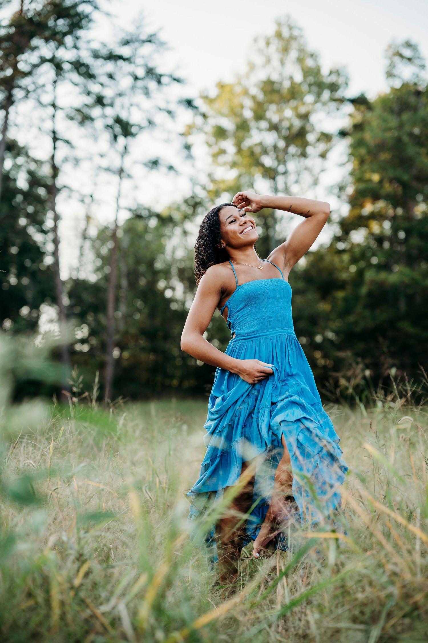 Bella twirling in blue dress in grassy Brandenburg KY field during senior photo session by ninefifteenphoto