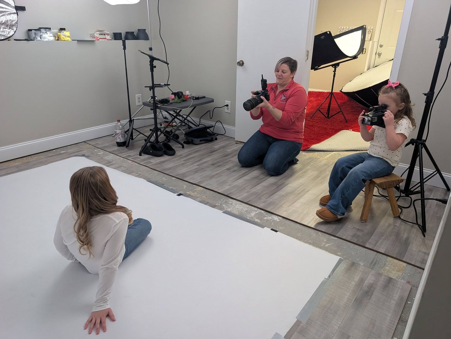 Photographer in red top photographing two girls in professional photography studio.