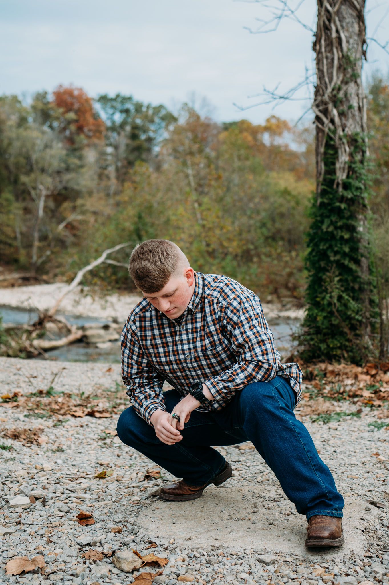 Mayson crouches on gravel during his fall FFA senior photos in Brandenburg Kentucky