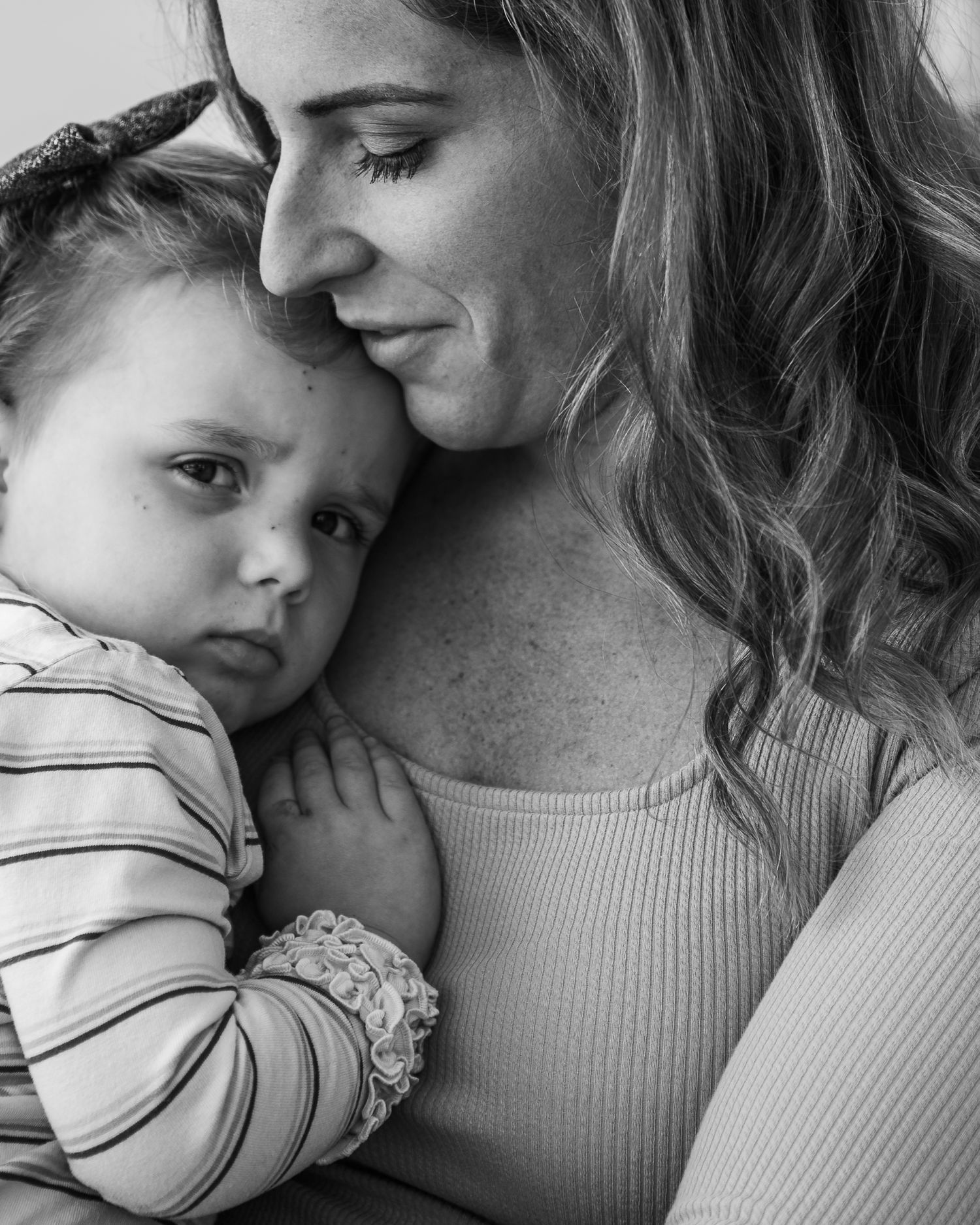 Black and white portrait of a mother tenderly holding her baby, sharing a quiet intimate moment together.