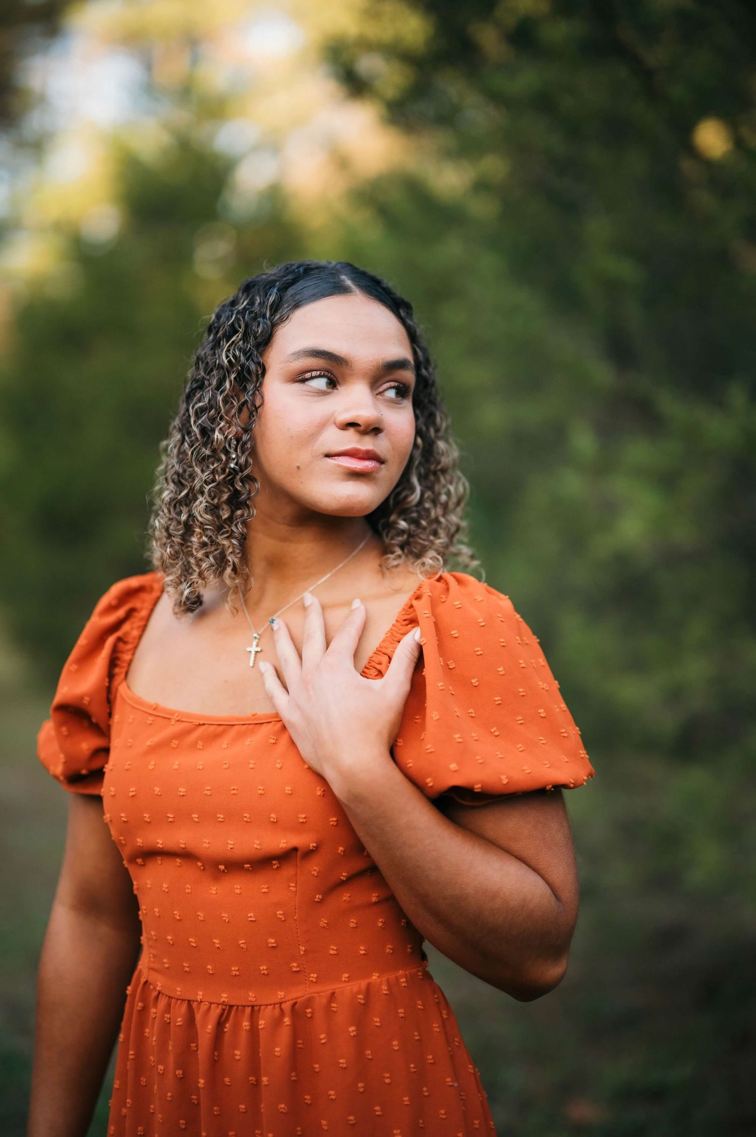 Senior in a burnt orange dress posing outdoors surrounded by fall colors in Brandenburg Kentucky.