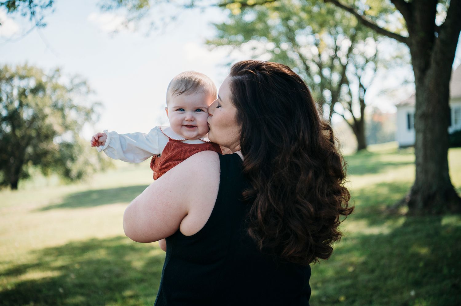 Tender moment of mom holding and kissing her baby during a Battletown farmhouse family session by ninefifteenphoto