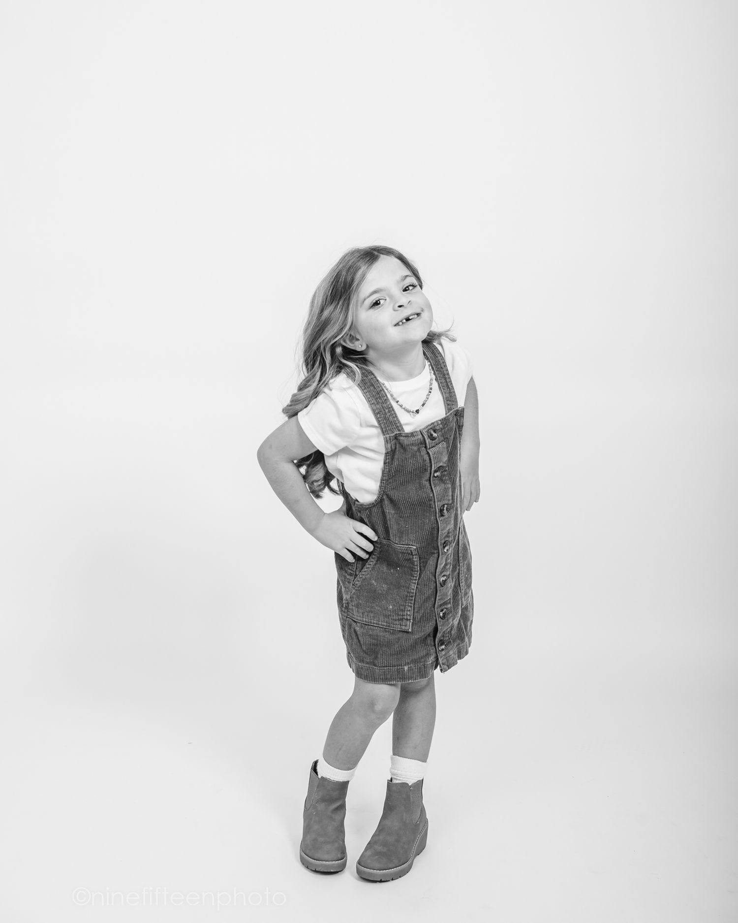 Studio personality portrait of a young girl smiling confidently in a textured vest against a neutral studio backdrop in Meade County KY