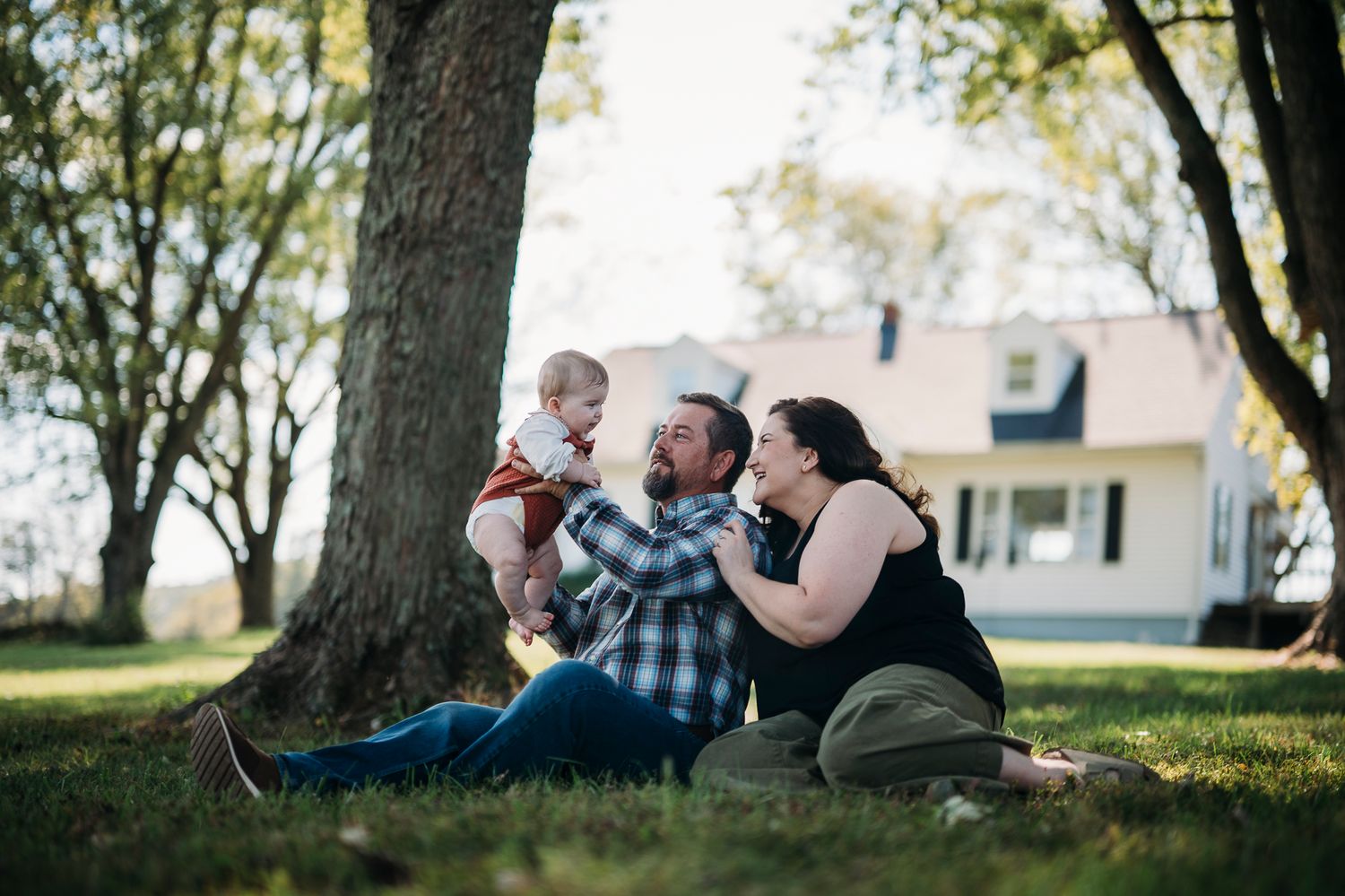 Candid family moment sitting together under the trees during a Battletown farmhouse session by ninefifteenphoto