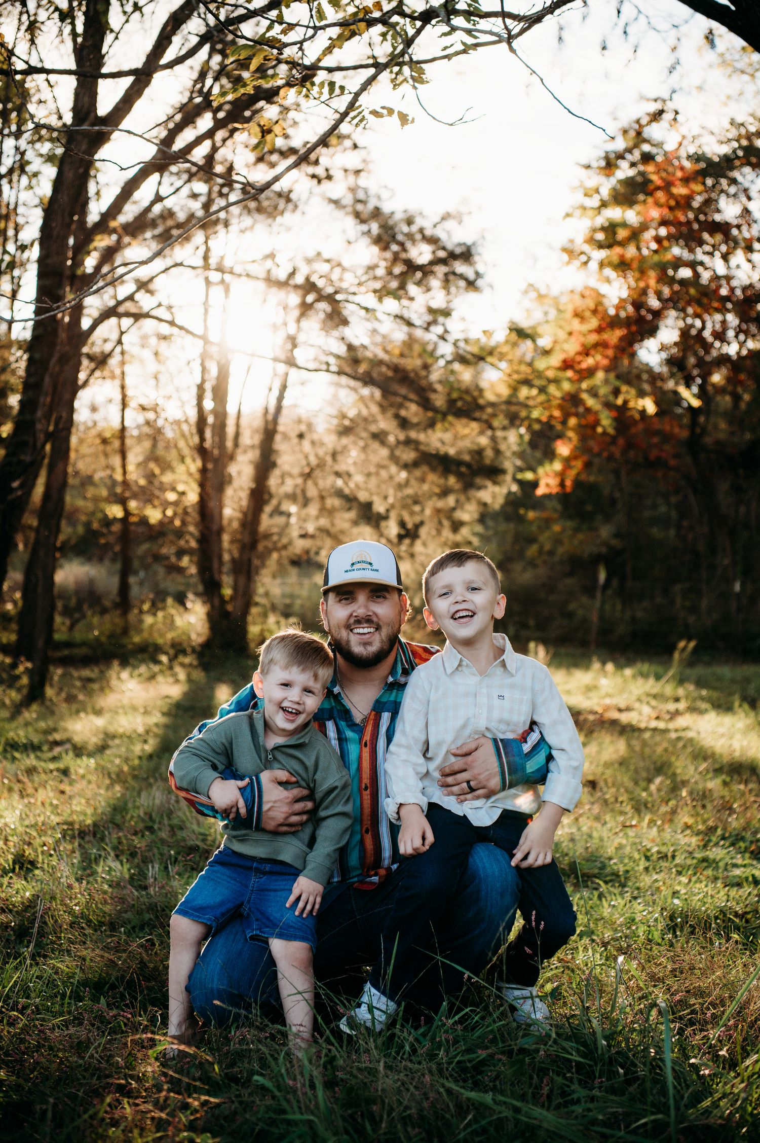 Family sitting together in glowing sunset field during photo session in Guston Kentucky