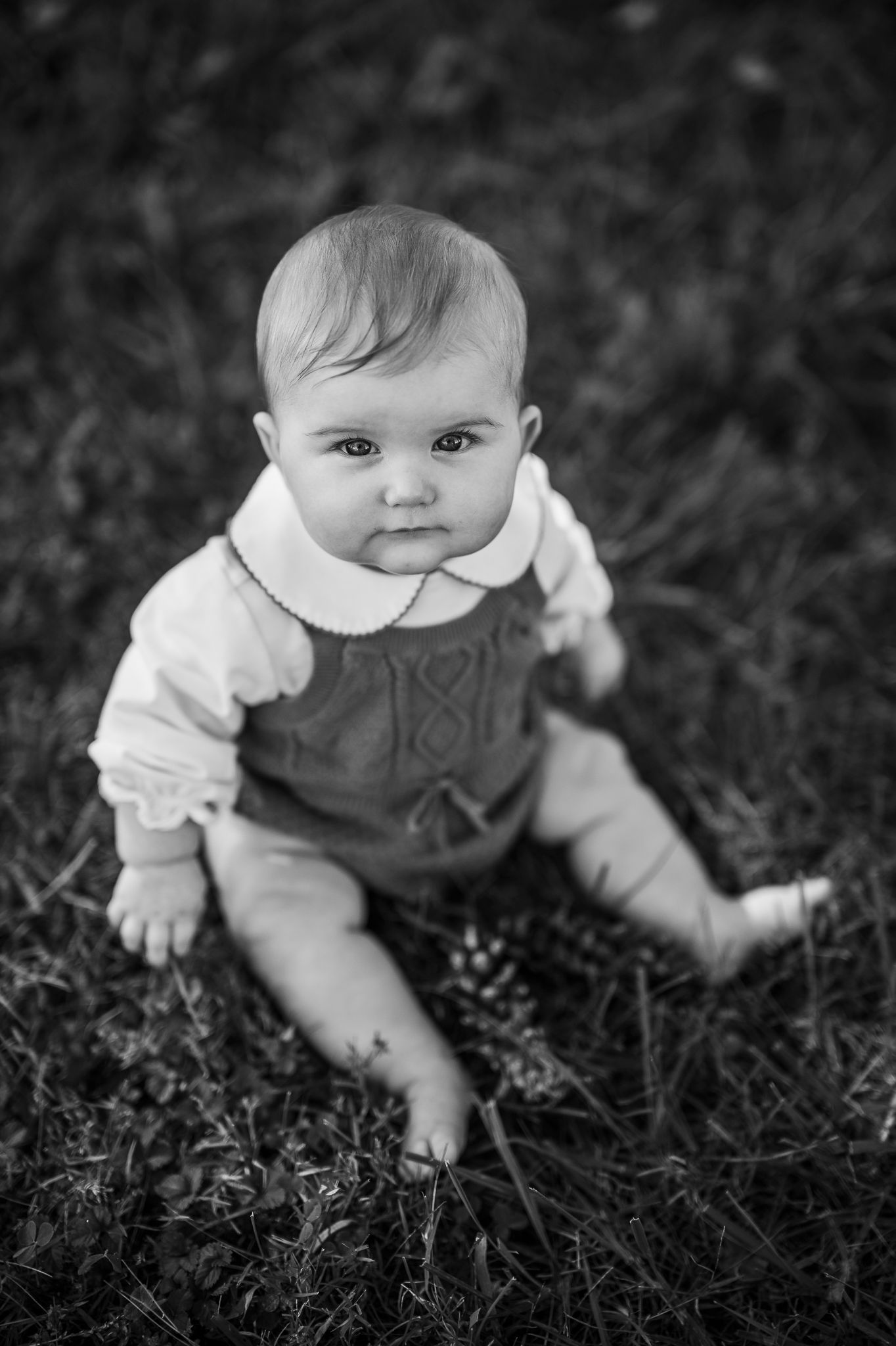Black and white portrait of an 8-month-old baby sitting in the grass during a Battletown KY session by ninefifteenphoto