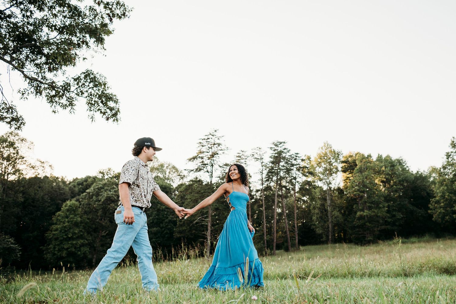 Couple walking hand in hand in Brandenburg KY field during senior photo session by ninefifteenphoto