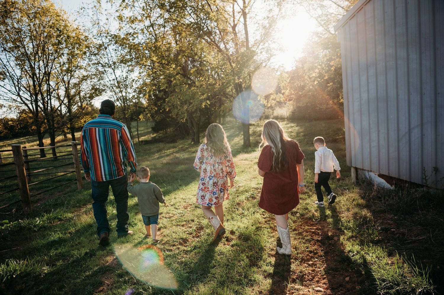Family walking through sunlit field toward barn in Guston Kentucky with warm golden light