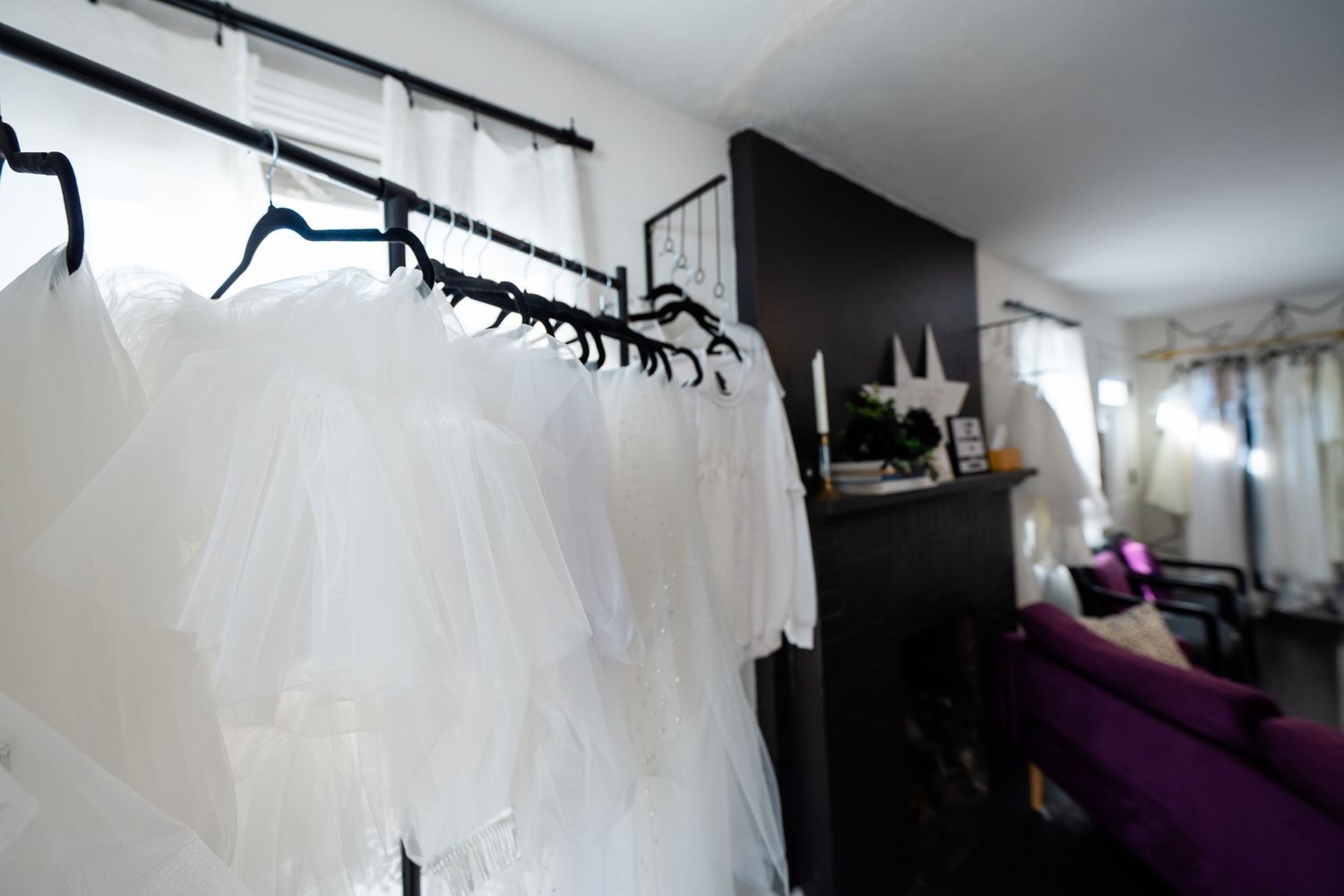 White wedding veils and gowns hanging on rack in a stylish bridal boutique showroom.