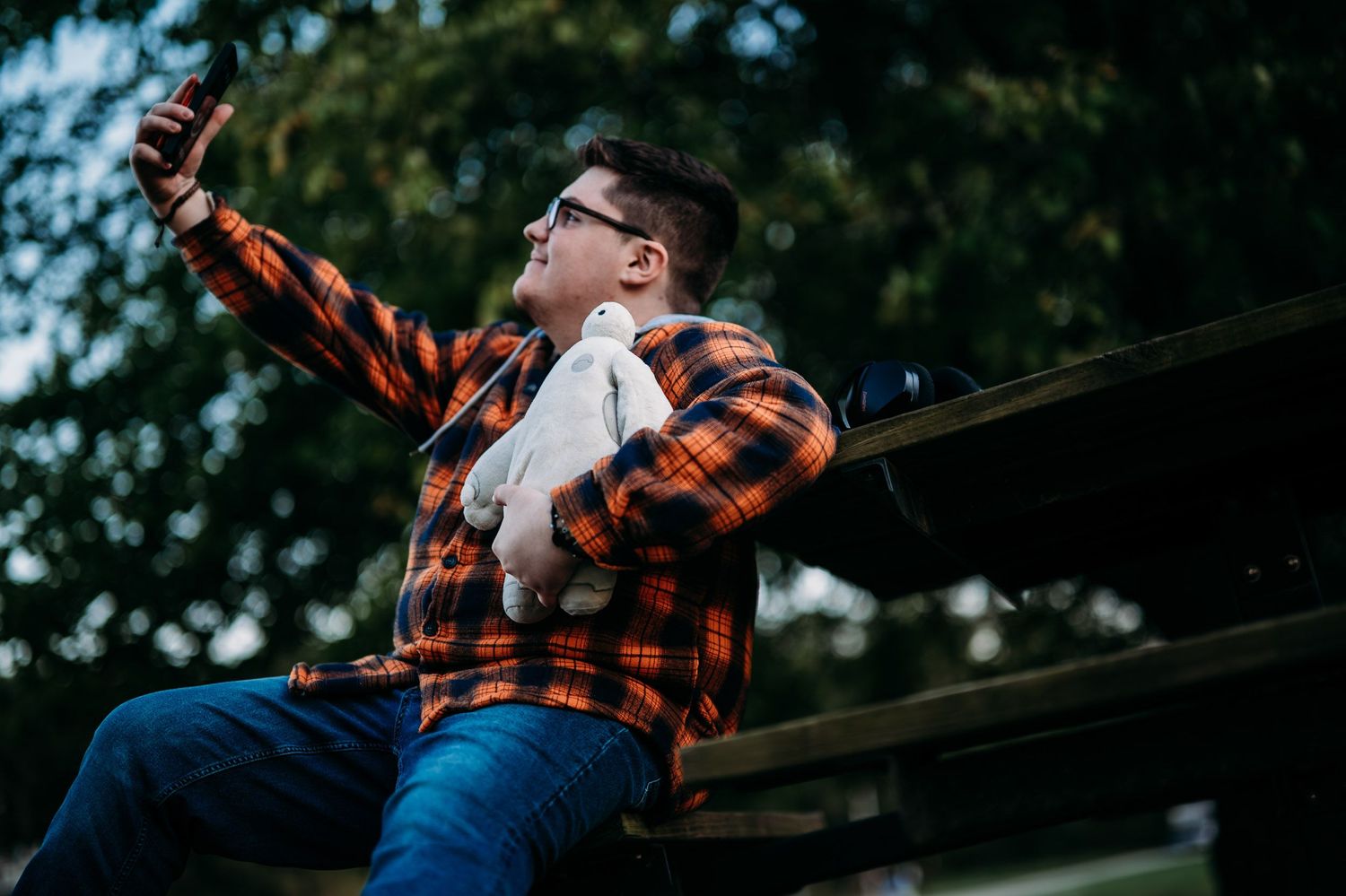 Luca laughing in his orange flannel during his senior photo session at a park in Brandenburg KY.